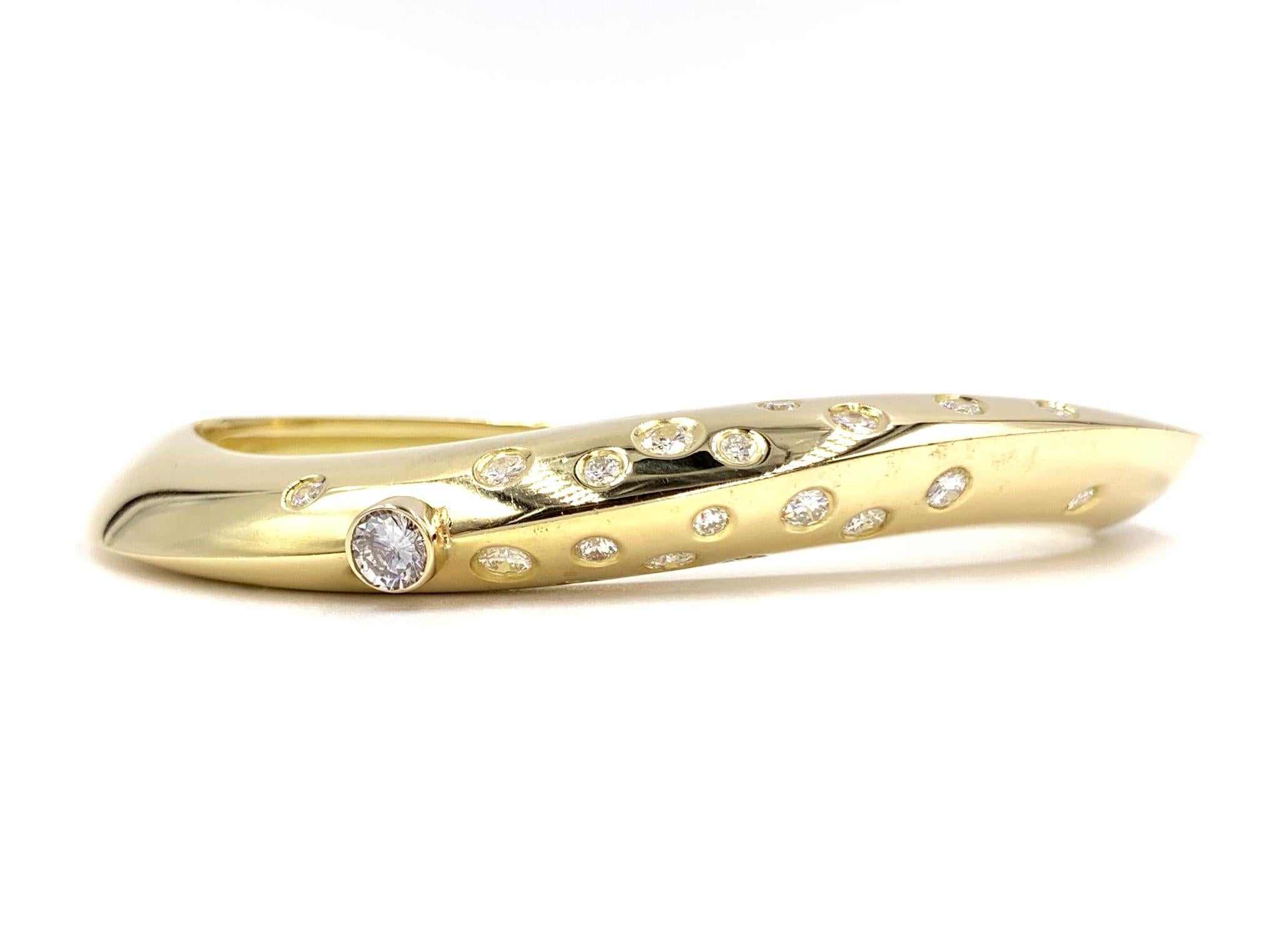 Created by Thomas Michaels Designs, this solid 18 karat yellow gold sleek oval bangle features 1.55 carats of round brilliant diamonds that are beautifully scattered throughout the top of the bracelet. Bangle has an asymmetrically designed curve