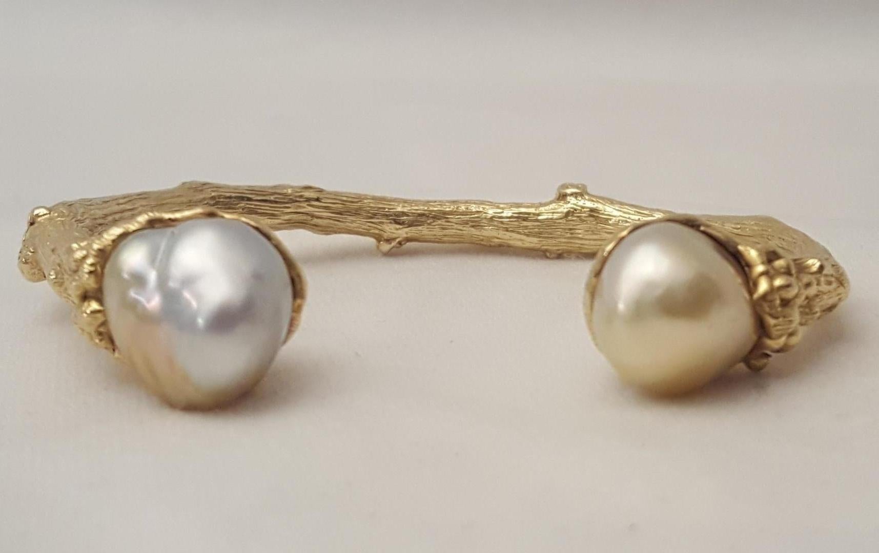 Stunning bracelet crafted in 18 karat yellow gold.  This piece is Solid, weighing in at an impressive 50.5 grams!  A curved, heavily detailed 'branch' design curves upward to present two baroque pearls sitting in cup like leaves.  Pearls are white
