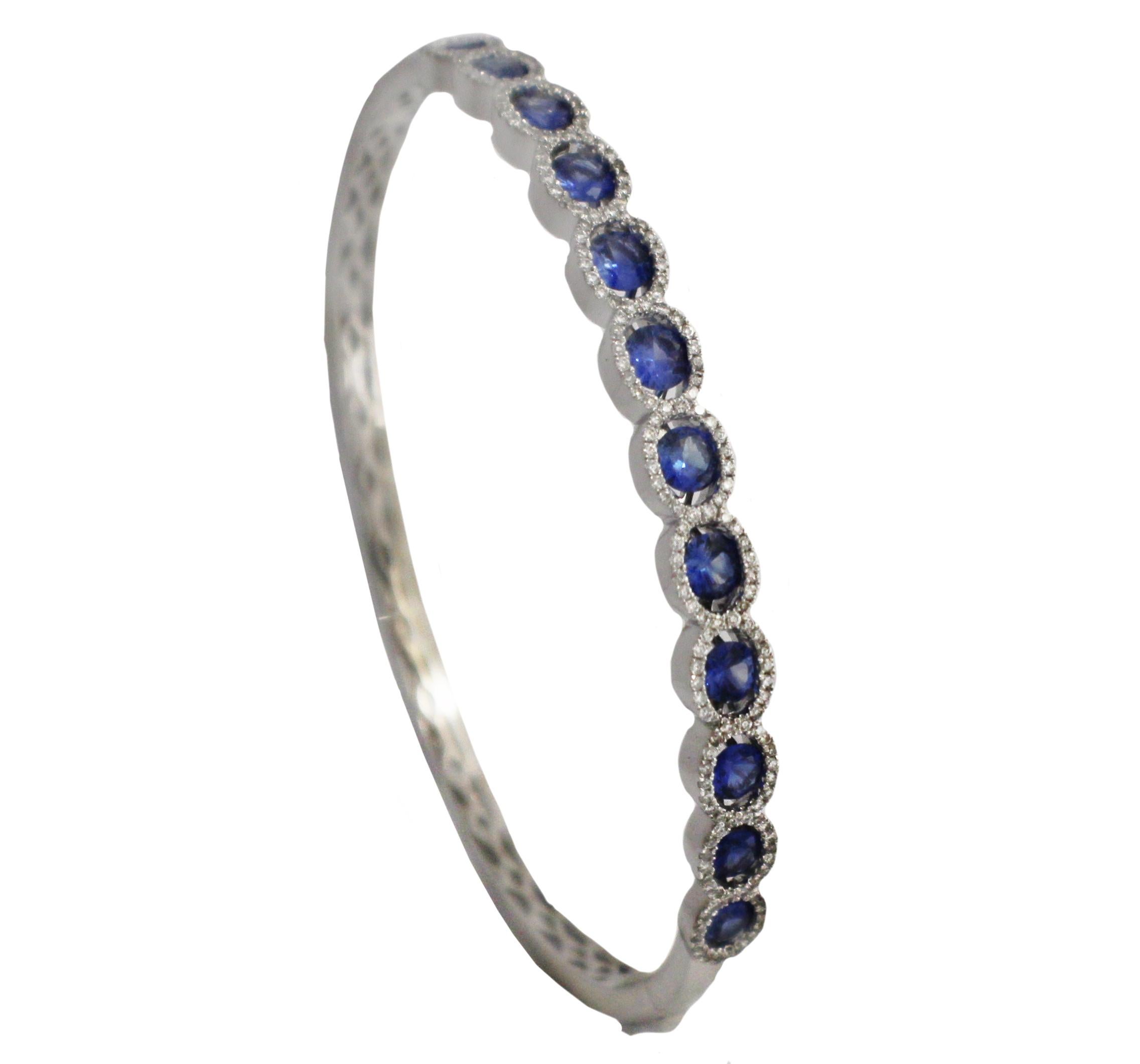 Never worn, brand new!  Crafted in 18 karat white gold this stunning bangle bracelet features twelve perfectly matched faceted oval Ceylon sapphires with a combined total weight of 2.09 carats.  Each sapphire is framed in micro pave white diamonds. 
