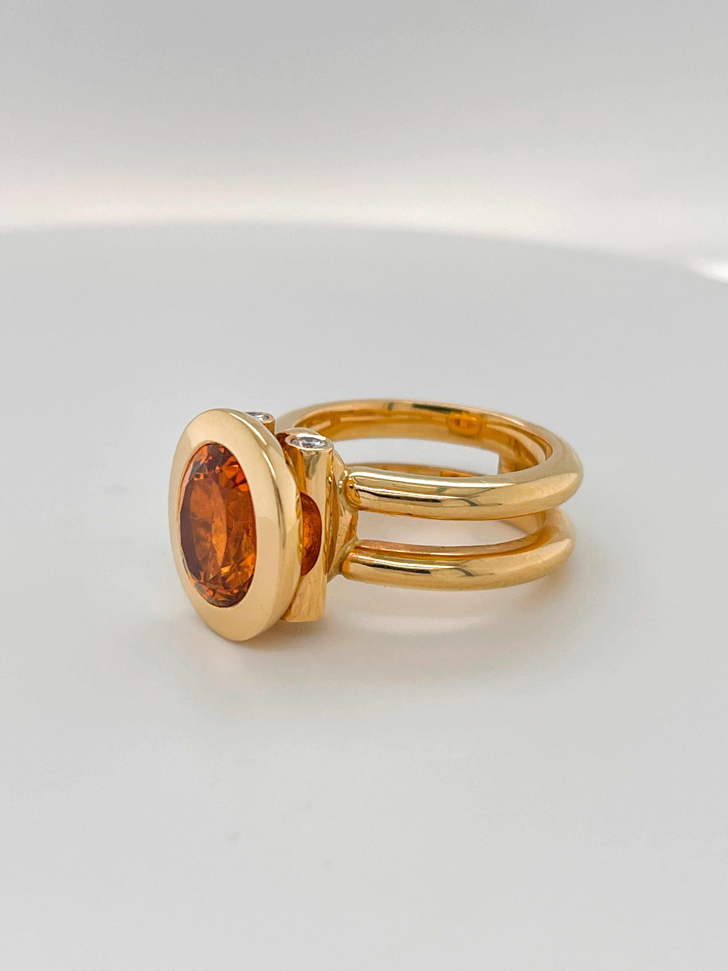 cocktailring aus 18 Karat Roségold mit einem 5,96 Karat warmen orangefarbenen Mandarin-Granatstein. 

Ovaler Schliff mit den Maßen 10 x 12,2 xmm.
Der Mandarin-Granat wird von 4 Diamanten VS1 G mit einem Gewicht von 0,20 Karat getragen.

Das Design