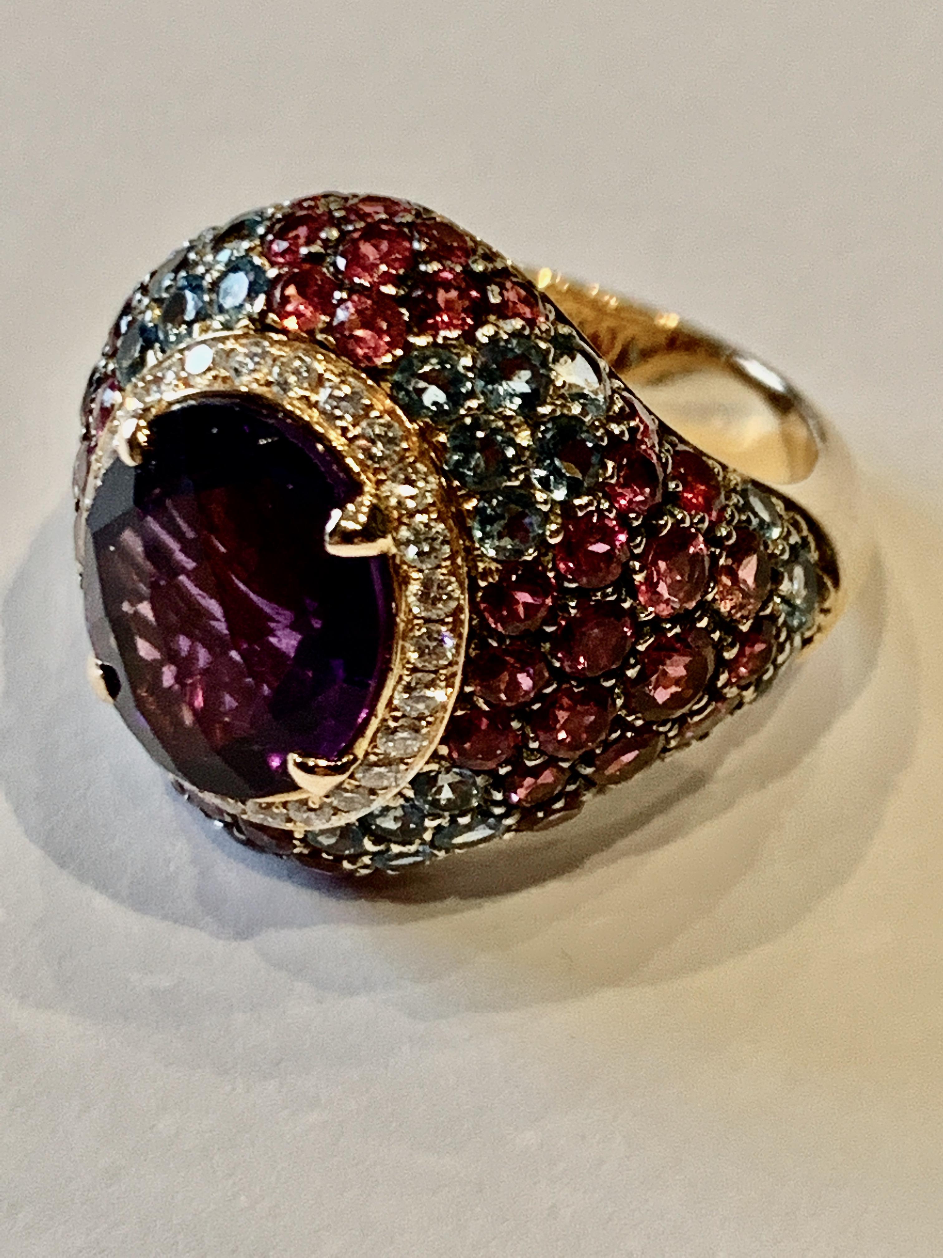 A feminine oval cut amethyst encircled by a delicate ring of brilliant cut diamonds surrounded by a pave set dome of vibrant rubellites and aquamarines.

Details
Amethyst Cocktail Ring with Rubellite, Aquamarine and Diamond
- 18 karat Rose Gold
-