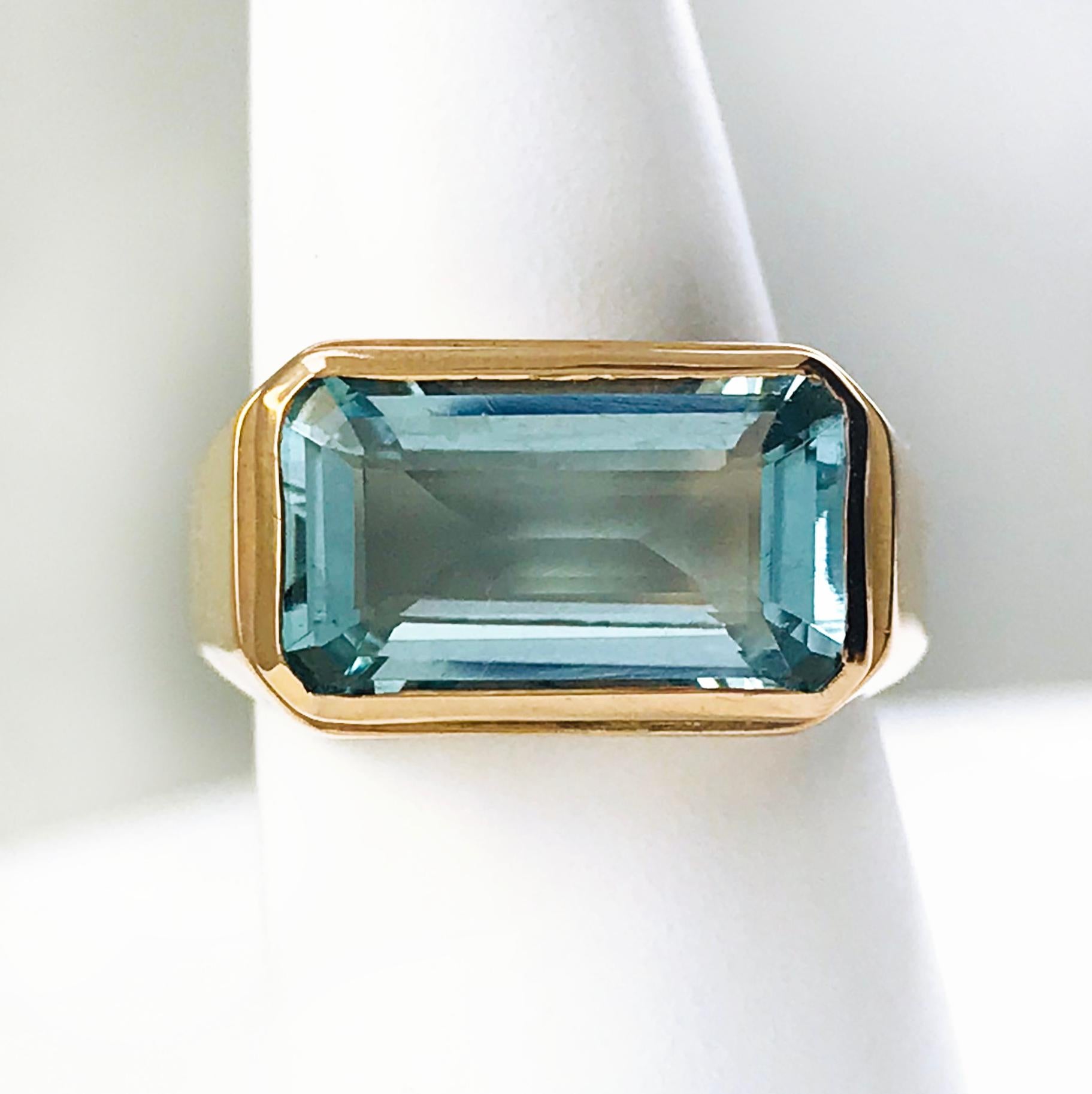 18 Karat Rose Gold Emerald-Cut Aquamarine ring. The ring design is simple, yet sleek and impactful, the total carat weight of the aquamarine is 7.5ct. The thick band starts near the bezel then tapers at the bottom of the ring. Engraved on the inside
