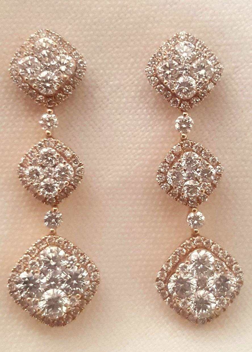 Brand new!  Fabulously crafted in 18 karat rose gold, these stunning pierced dangle earrings feature three separate diamond encrusted stations.  Top is stationery and two dangle effortlessly and move with your every step. Three stations are
