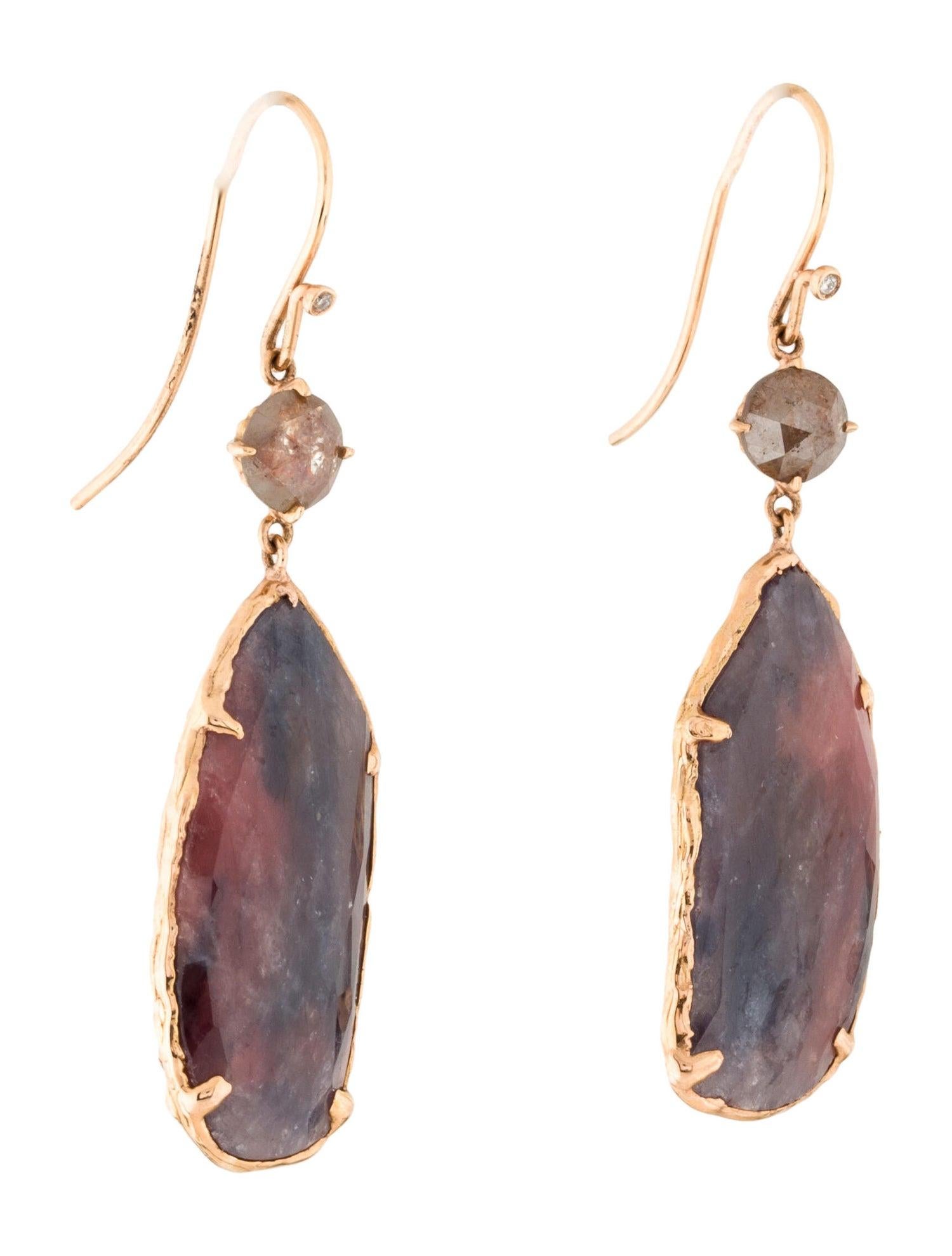  These stunning Sapphire Slice Dangle Earrings are a true masterpiece, crafted with 18 Karat Rose Gold. The intricate design showcases a round brilliant rustic diamond and a unique free form Sapphire Slice, adding an element of individuality to the