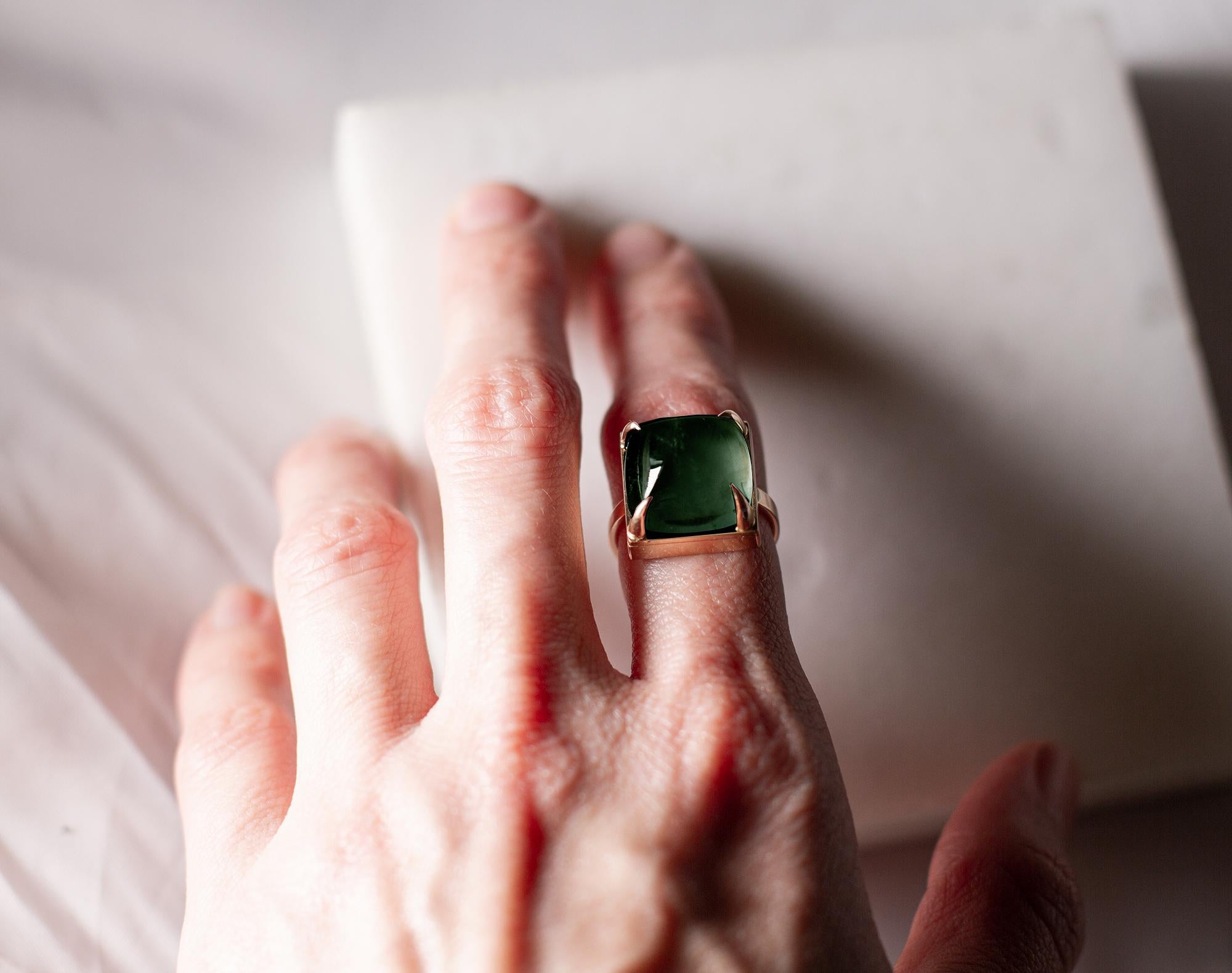 This contemporary engagement ring is made of 18 karat rose gold with sugarloaf cut natural green tourmaline (10,67 carats, 11,5 mm/0,45 inches). 

When for most of the gem it works the way: the smaller prongs the better. This is the shape and size