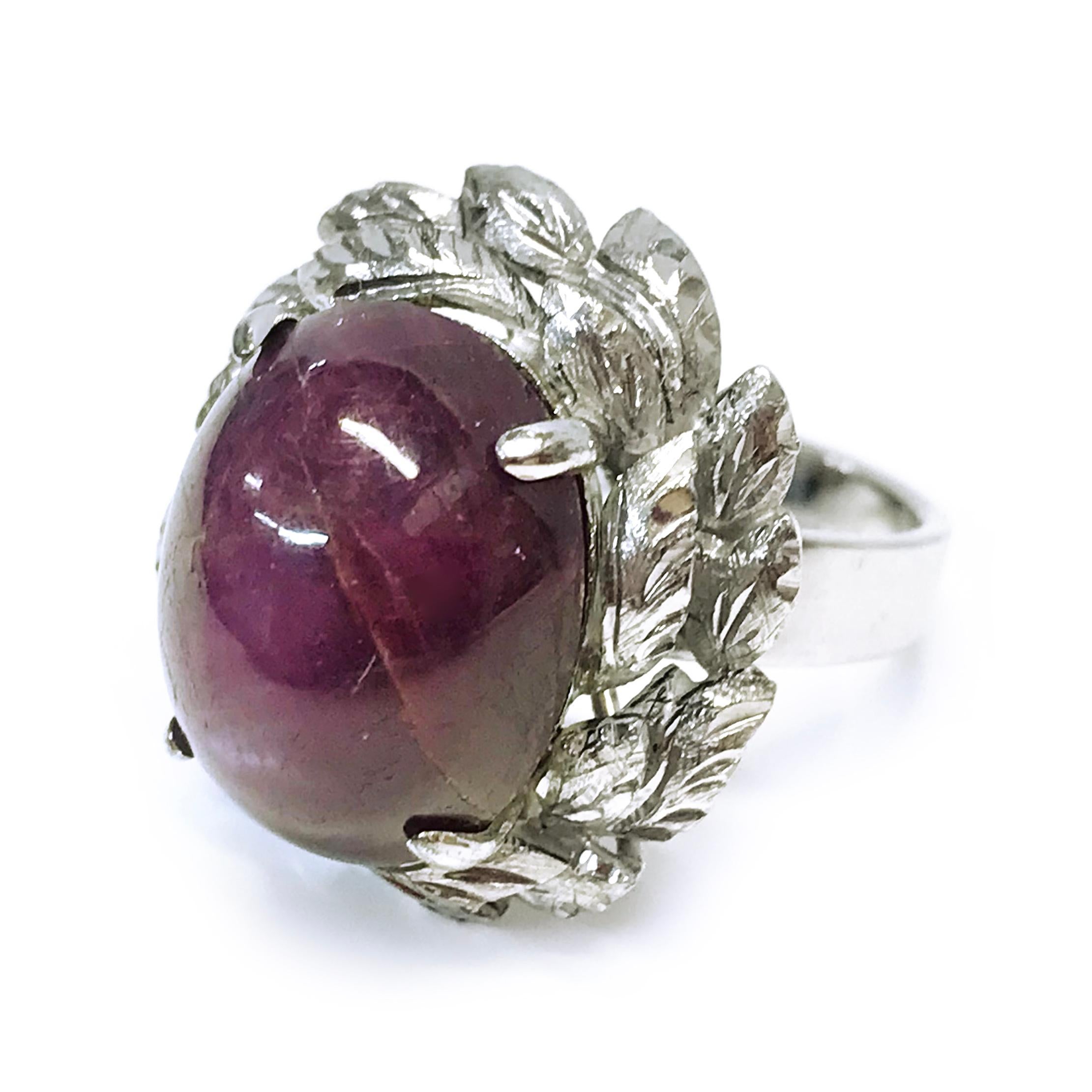 18 Karat White Gold Ruby Star Sapphire Ring. The natural Ruby Sapphire measures 16mm x 12mm, and is four-prong set with two tiers of diamond-cut leaves around the setting. The six-pointed star has a good presence with light. The ring size is 6 1/4