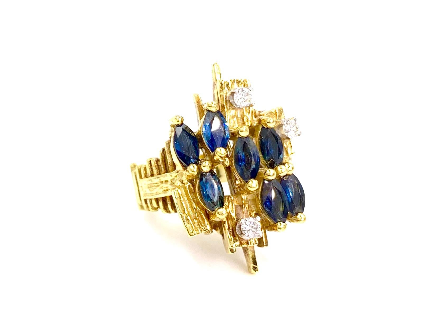 A truly unique mid-century modern style 18 karat yellow gold blue sapphire and diamond ring. Vertical bars are arranged in an abstract silhouette with seven marquise cut blue sapphires staggered at 1.45 carats total weight. Three round brilliant