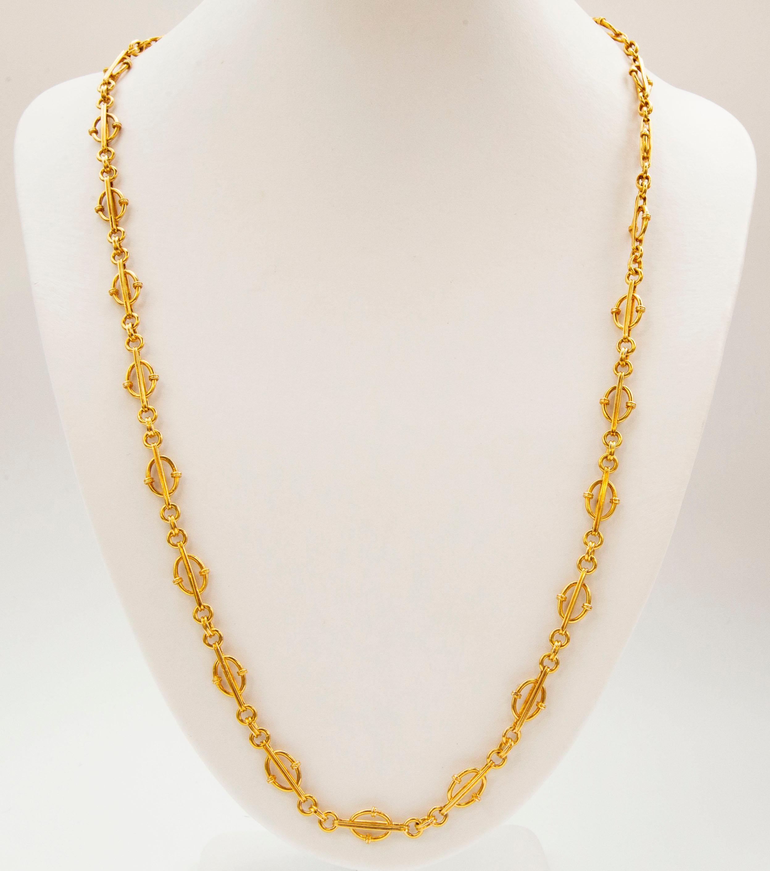 A vintage 18 karat solid yellow gold chain necklace featuring multiple units consisting of  three connected circles attached to elongated links filled with open oval frames.  The necklace has an unusual  chain design. Its color is intense and vivid