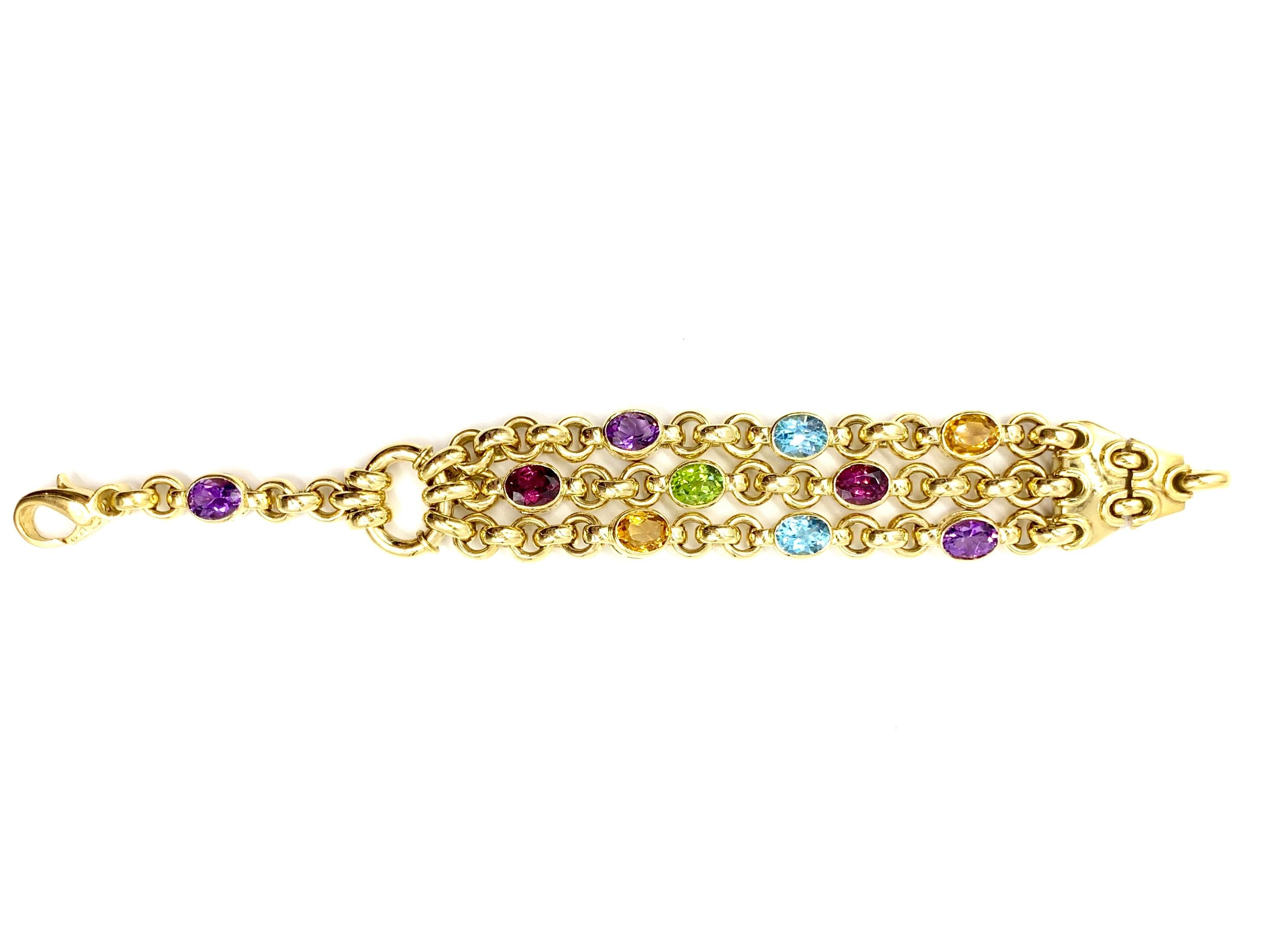 A very well made, high quality solid 18 karat yellow gold heavy link bracelet featuring three chains with scattered bezel set faceted oval semi precious gemstones. Gemstones are as follows: 3 amethysts, 2 Swiss blue topaz, 2 rhodolite garnets, 2