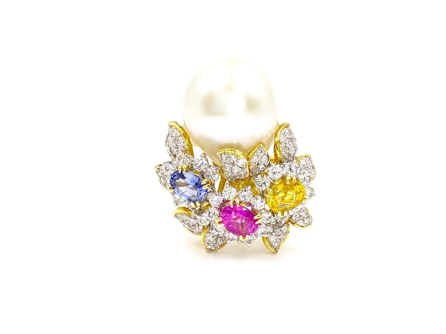 A substantial, high quality 18 karat gold floral cocktail ring featuring a 14.9mm genuine ivory south sea pearl, 2.27 carats of sapphires and 1.49 carats of bright white diamonds. Pearl is smooth with a natural shape and beautiful luster. Pink, blue