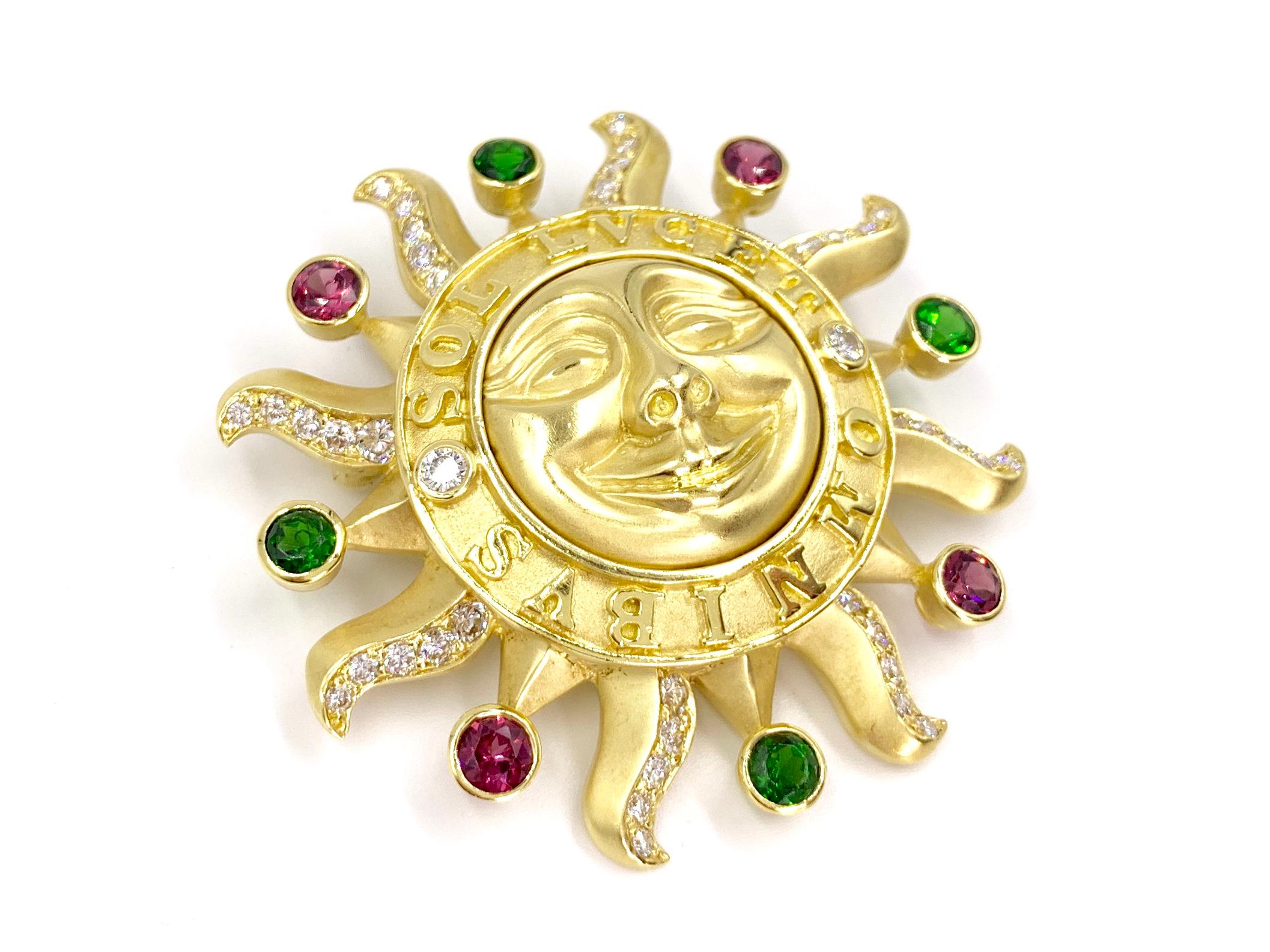 A solid and very well made 18 karat yellow gold smiling sun brooch adorned with white diamonds and vibrant pink and green tourmaline gemstones, crafted by SeidenGang jewelry company. Sun is carved with the Latin saying 