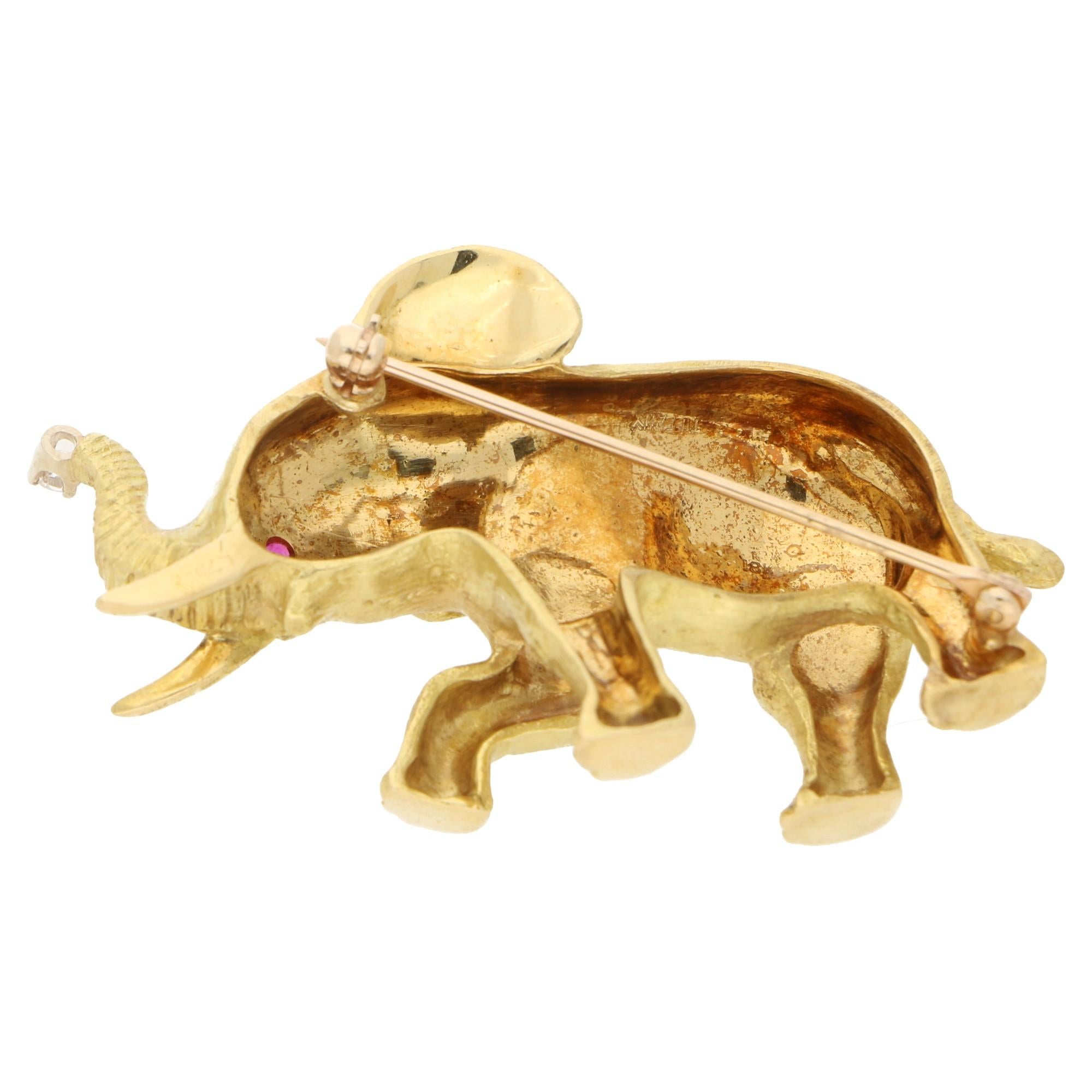  A dramatic Tiffany & Co elephant brooch in 18-karat yellow gold. The brooch is designed as a naturalistic moving elephant with the front right leg and the trunk raised powerfully, the trunk accented at the tip with a round brilliant-cut diamond of