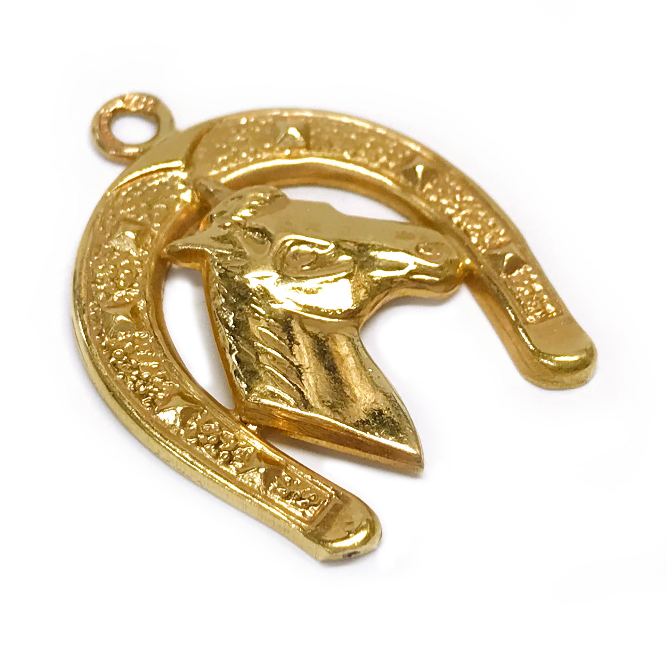 18 Karat Toliro Horse and Horse Shoe Pendant. The pendant features an image of a horse head from its side framed by a horseshoe. The majority of the pendant has a smooth shiny finish, with some detail in the horse mane, eye, and nostril and a