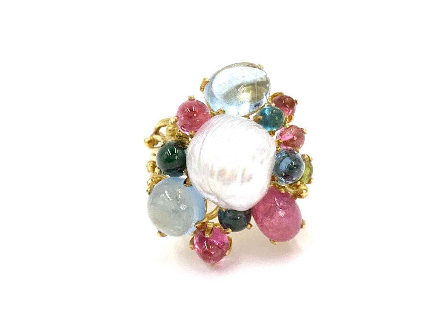 An artistic and whimsical 18 karat yellow gold wide ring featuring beautiful multi-color cabochon cut tourmaline gemstones and a textured lustrous 11mm white pearl. A total of 12 tourmaline gemstones in varying sizes range in color from vibrant pink