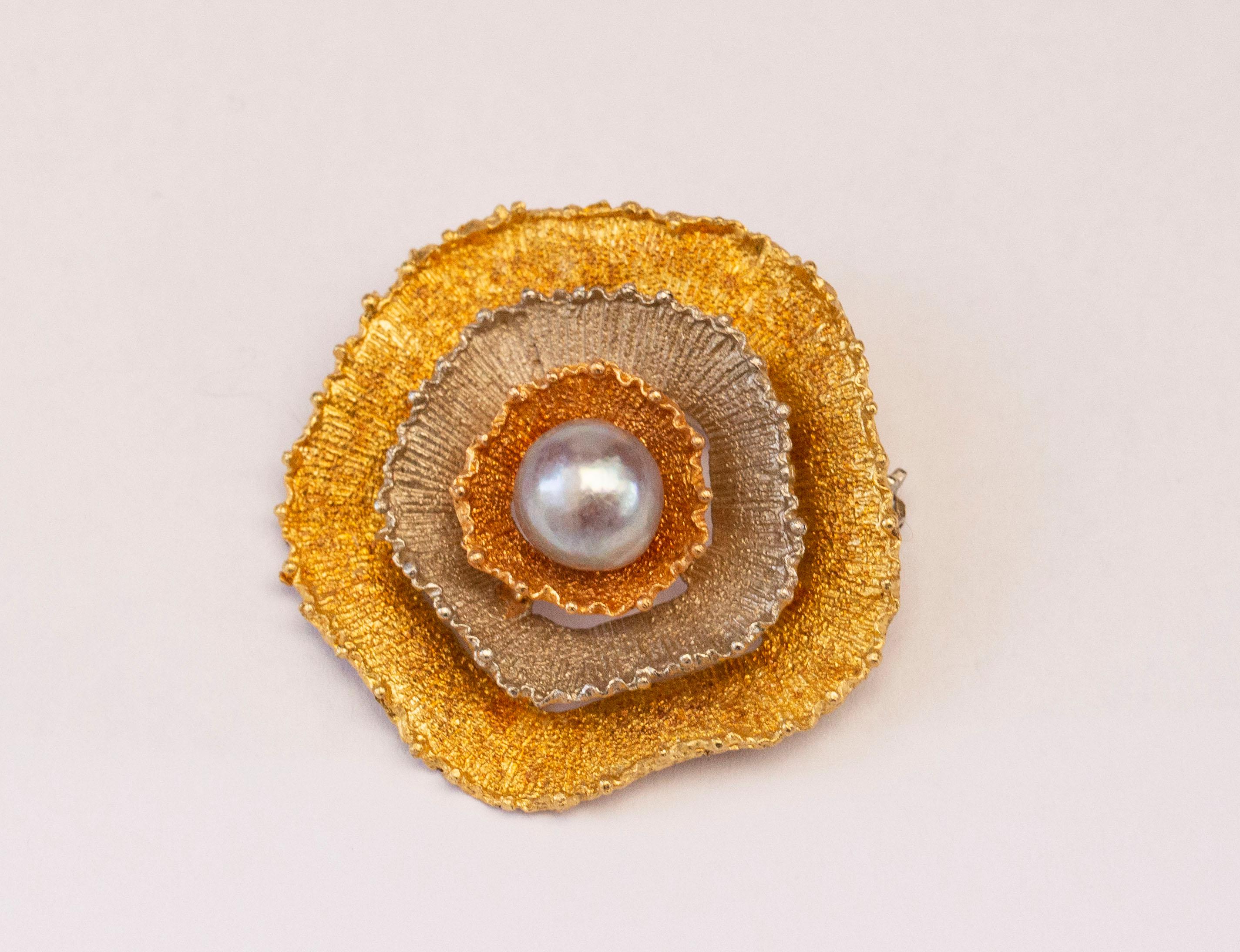 A vintage 18 karat tricolor (yellow, white & rose) gold brooch in a form of a round abstract flower with a gray pearl in the middle. The brooch features a precise and intricate finish. The brooch could be a great present idea for a woman of any age