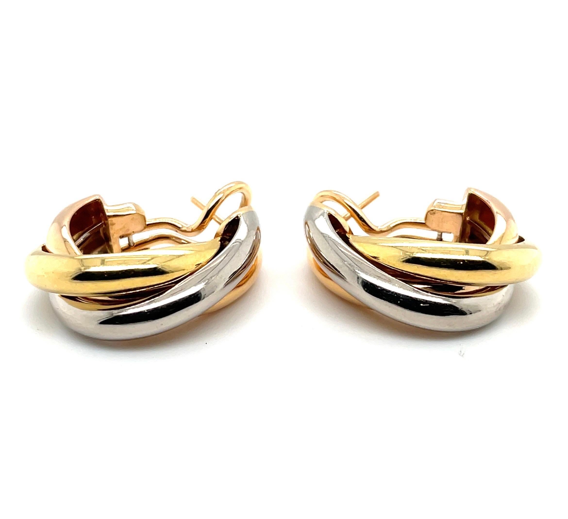 Classic pair of 18 karat tricolor trinity half-hoop ear clips by Cartier 1995. 

Elegant half-hoop earclips, designed as slightly bombé, intertwined bands in yellow, white and pink gold 750. Clip system with studs. Signed Cartier and numbered