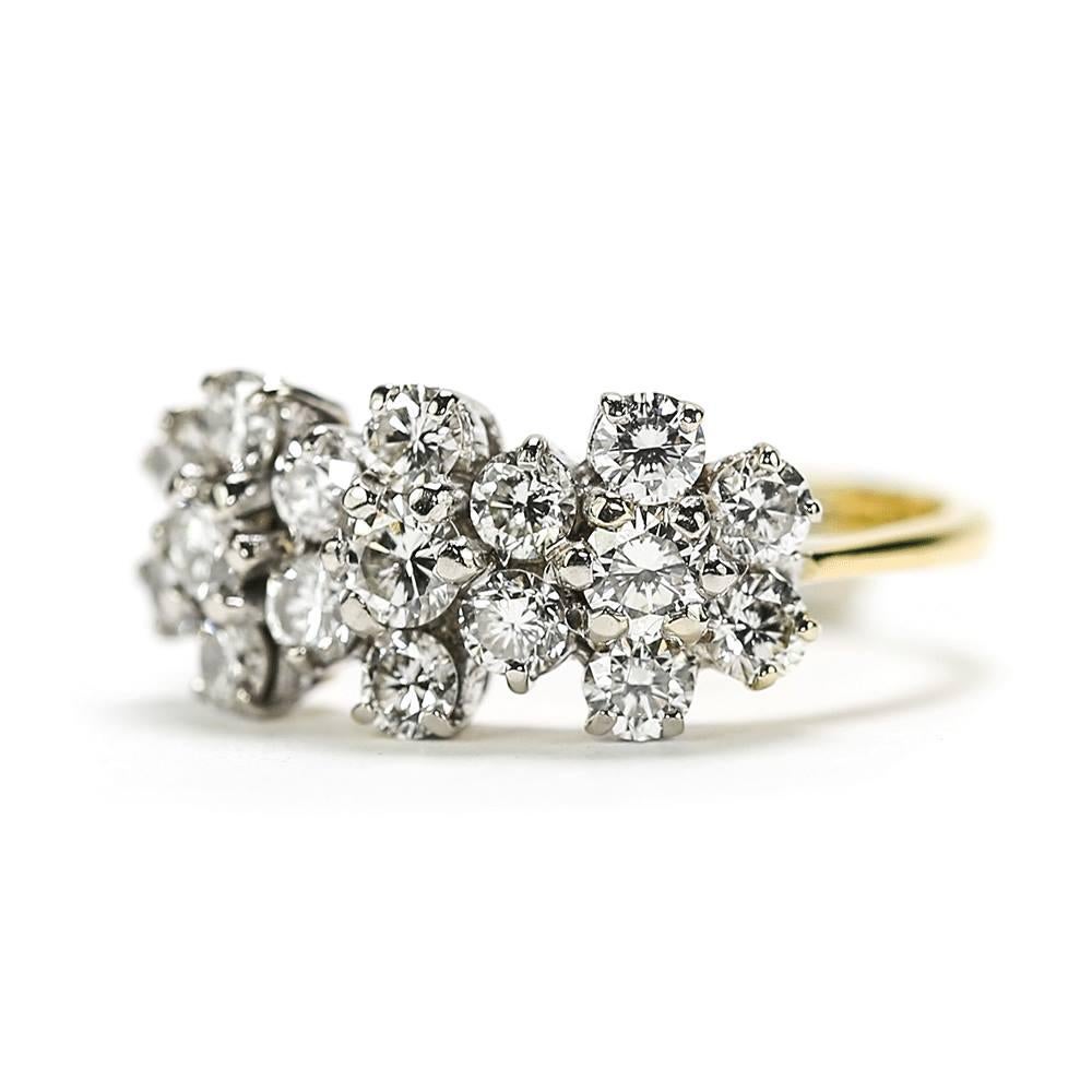 A striking triple cluster diamond ring designed as three daisy clusters in a broad half eternity style setting. Each ‘flower’ cluster comprises a six 0.5ct approx. diamond collection with a centre stone of approx. 0.10ct diamonds. The brilliant cut