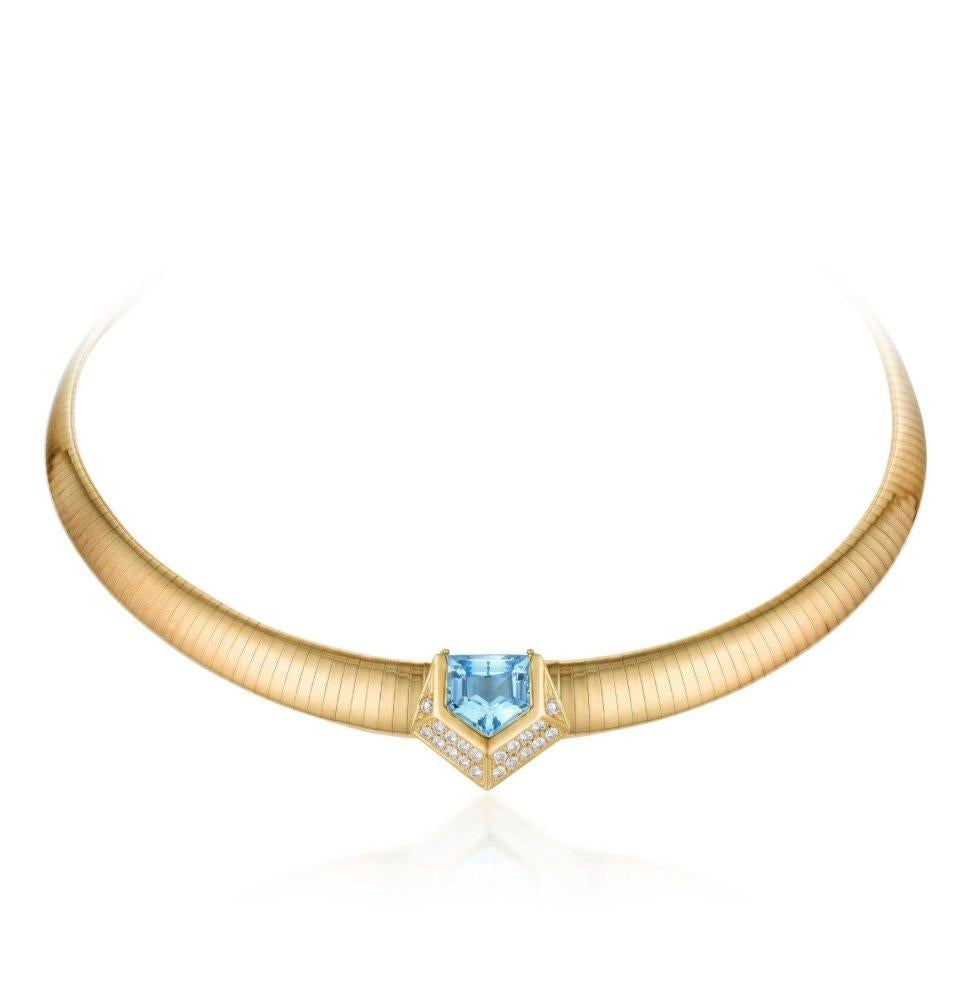 Crafted in 18 karat gold this amazing tubogas style collar necklace features an epaulet-cut blue topaz weighing approximately 8.25 carats; accented by 20 round brilliant-cut diamonds weighing a total of approximately 1.10 carats, most with F-G color