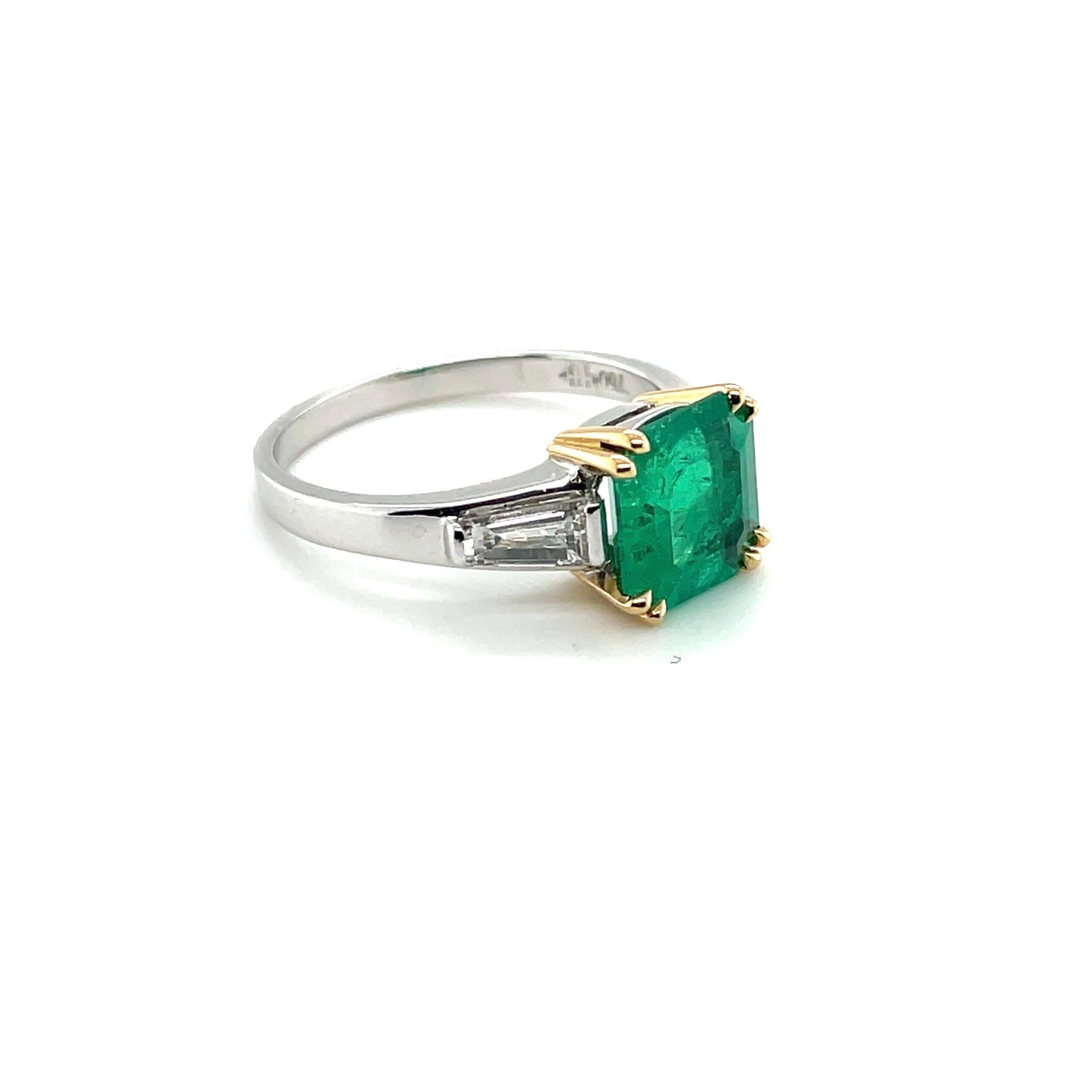 18 karat white and yellow gold emerald and diamond three-stone ring. 

Elegant ring, centering upon 1 octagonal, luminous emerald of circa 1.80 carats, set in yellow gold prongs and flanked by two tapered-baguette-cut diamonds totalling circa 0.60