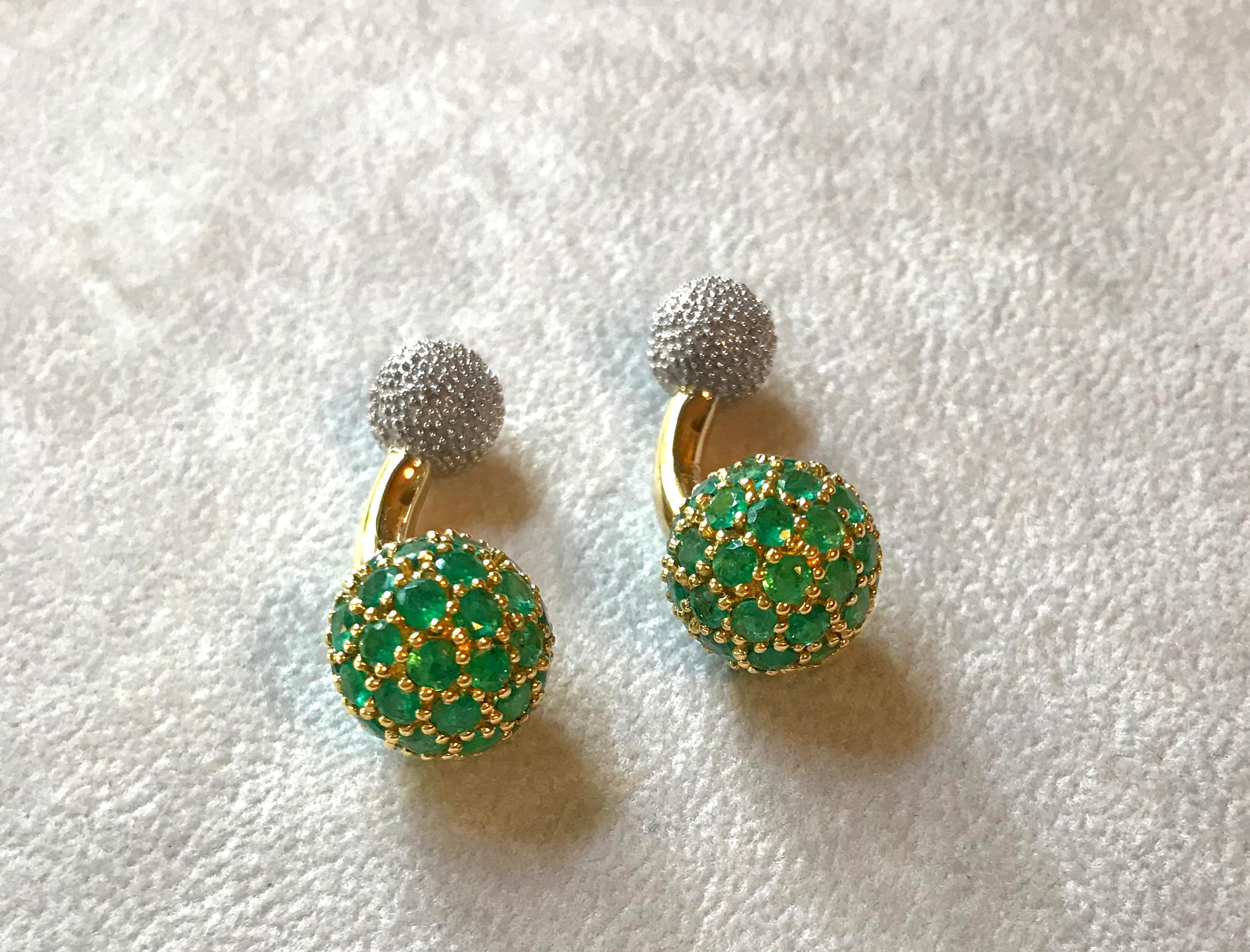 These elegant cufflinks are made in 18k gold , the large spherical front face is completely covered in emeralds, while the toggle is shaped as a smaller sphere with a multi-faceted texture made in 18k white gold . A curved post  made in 18k yellow