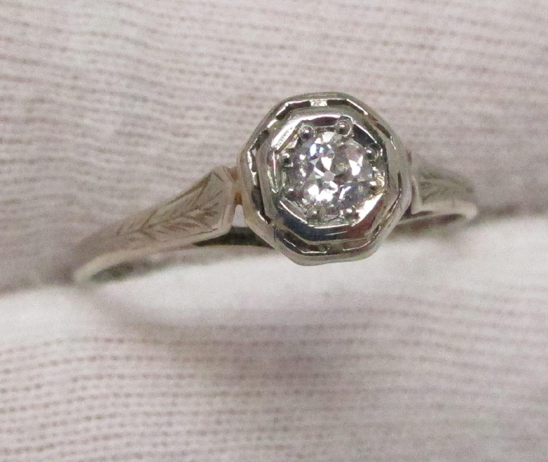This fetching Art Deco 18K white gold filigree engagement ring features a 0.20ct Old Mine Cut diamond, H color and SI1 clarity. This ring is very comfortable to wear. The diamond is bead set, so there are no prongs to catch on things.

The ring is a