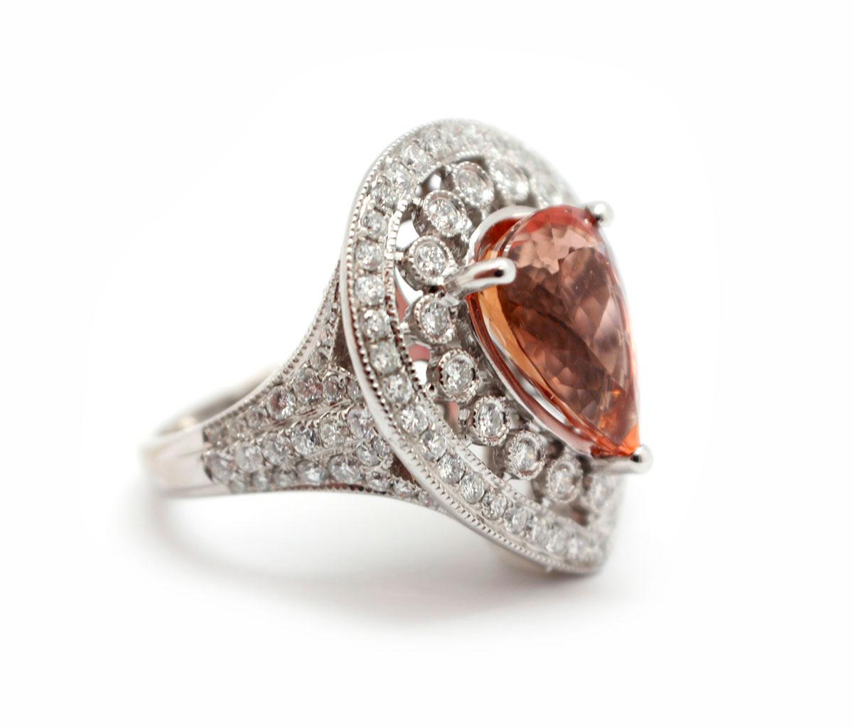 This stunning piece is made in solid 18k white gold. It features a pear-cut 4.50-carat Imperial topaz at its center. The stone is adorned by stunning diamonds that echo the pear shape of the stone. The diamonds have an additional weight of 1.18