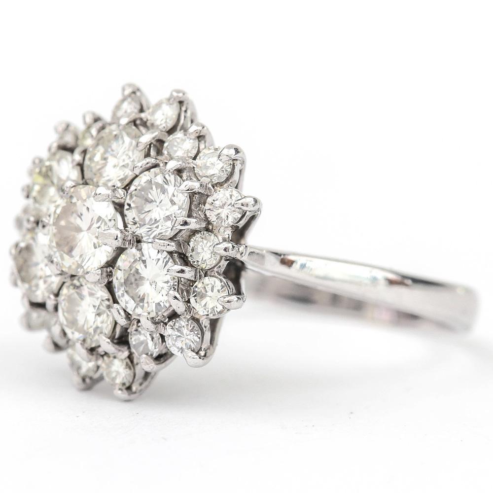 A traditional cluster ring with 5 principle diamonds at the centre and graduated diamonds around which is modelled in 18 karat white gold and comprises 25 diamonds, with a centre stone of 0.40ct and a total estimated 2.40ct. The setting is a cage