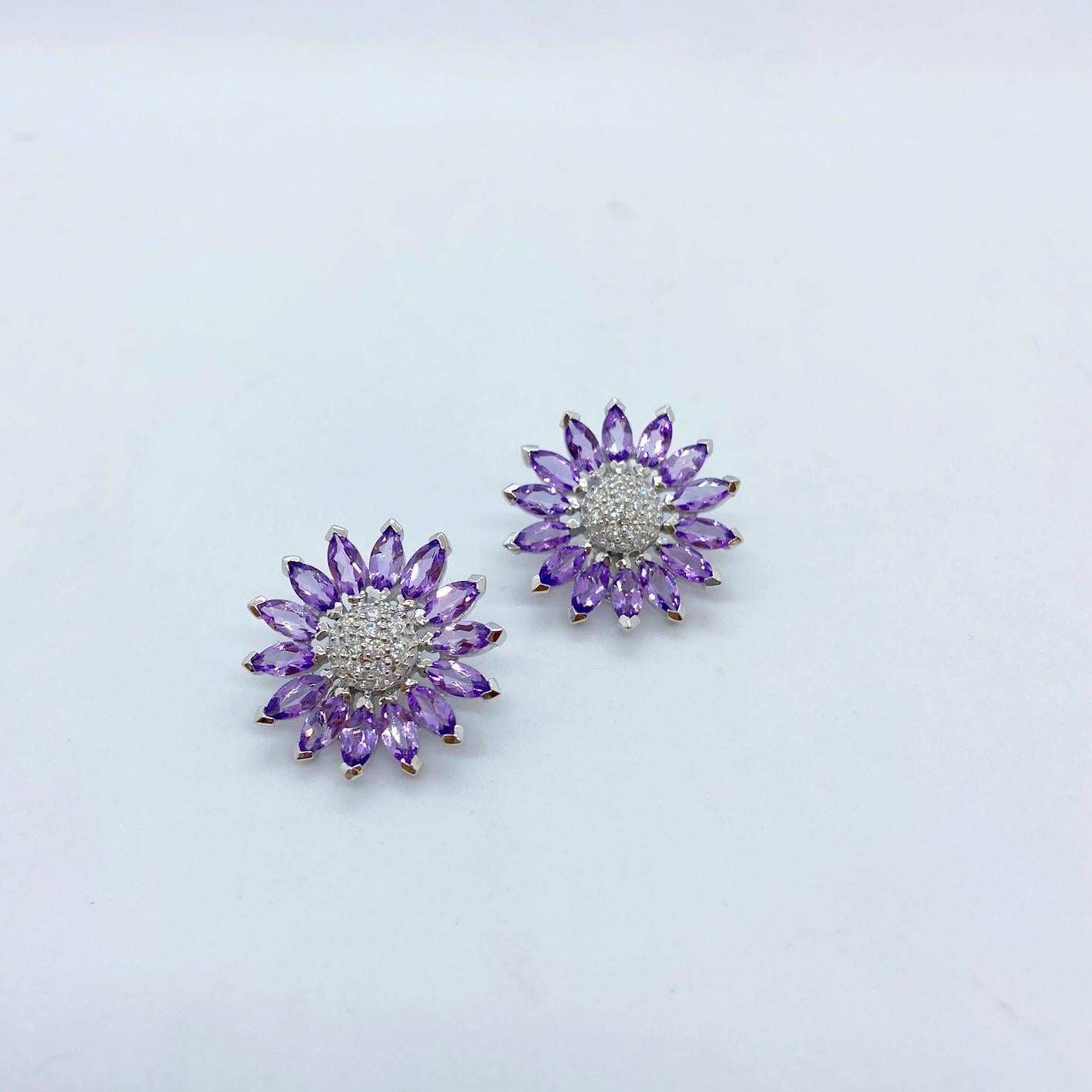 A pretty pair of ear clips.
These 18 karat white gold earrings are designed as sunflowers. Each earring has 14 marquis Amethyst stones as the petals , and 10 round brilliant Diamonds set in the center. The earrings have a post and Omega back and can