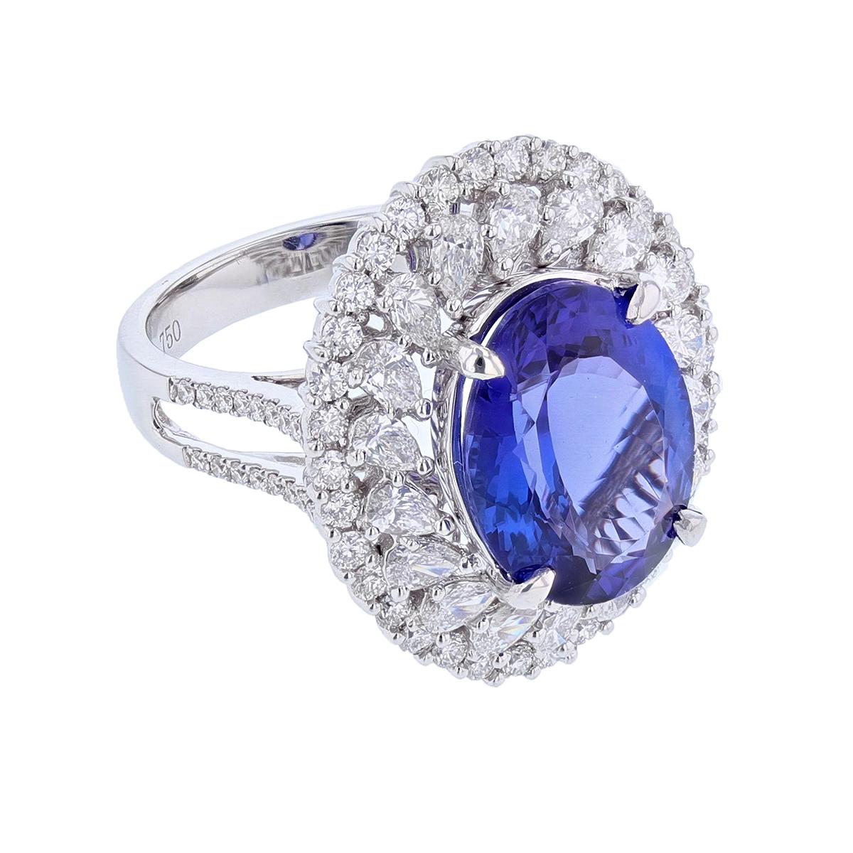 This ring is made in 18 karat white gold. The center stone is an oval cut tanzanite weighing 6.53 carats and is prong set. The mounting features 66 round cut, prong set diamonds weighing 0.96 carats and 18 pear shape, prong set diamonds weighing
