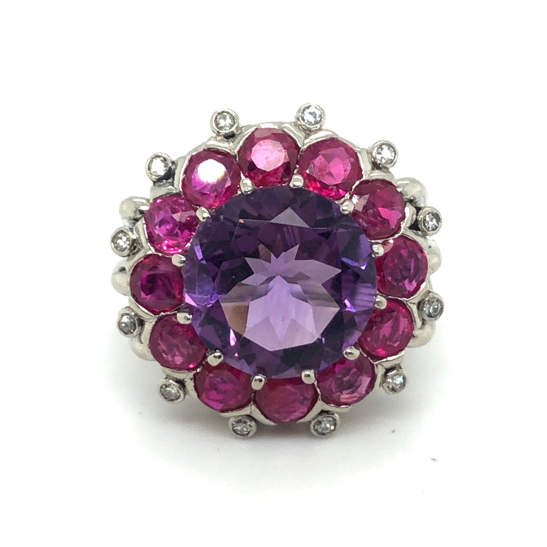 Festive 18 karat white gold amethyst ruby and diamond cocktail ring.
Cocktail ring set with a round amethyst of circa 5 carats surrounded by an entourage consisting of 12 round rubies totalling circa 4.20 carats and 12 single-cut diamonds totalling
