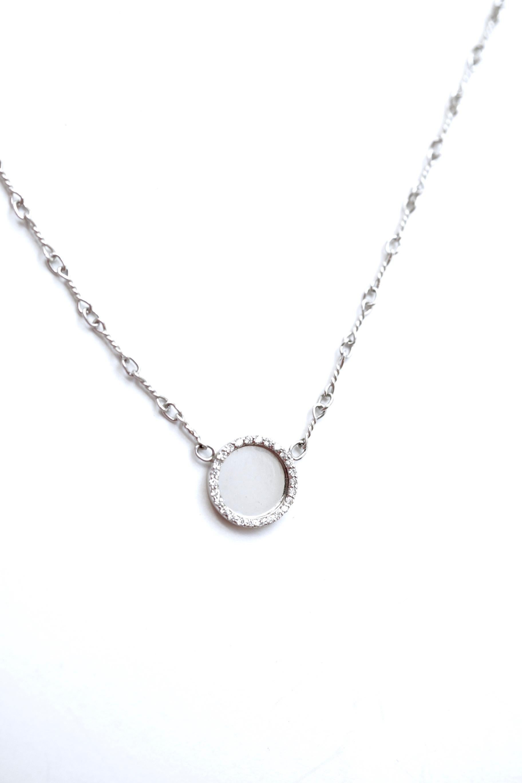 Murree Dot Necklace 
A 15-inch eighteen-karat white gold chain suspending a 10mm circular pendant, framed with a collection of white diamonds.  Filling the center of this necklace, is a very fine and highly polished piece of eighteen-karat white