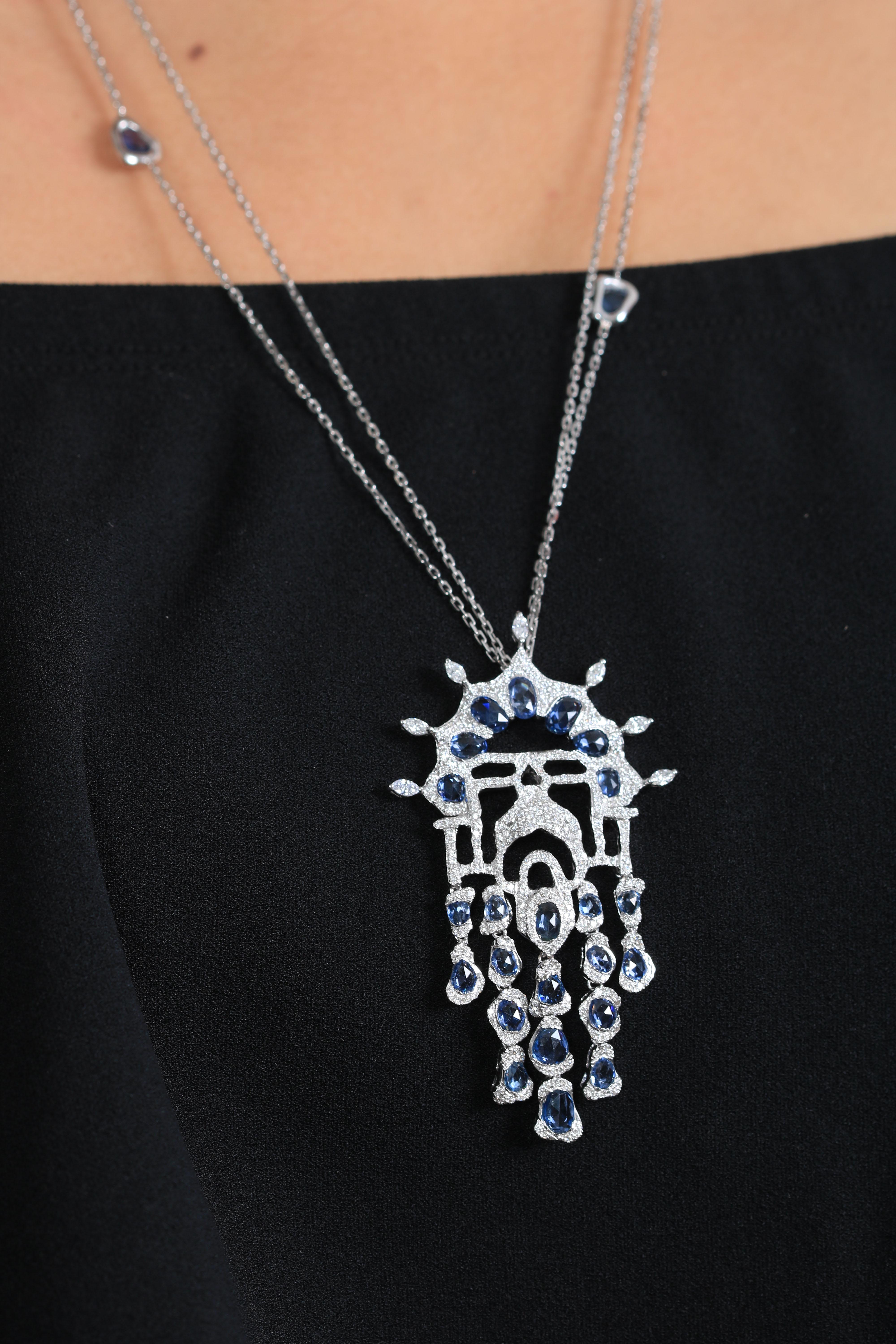 Le pendentif Arabesque est soigneusement fabriqué à la main avec des accents féminins et floraux exquis. Le pendentif est composé de saphirs bleus et de diamants blancs lourdement sertis, dont les différentes coupes et formes se rejoignent pour
