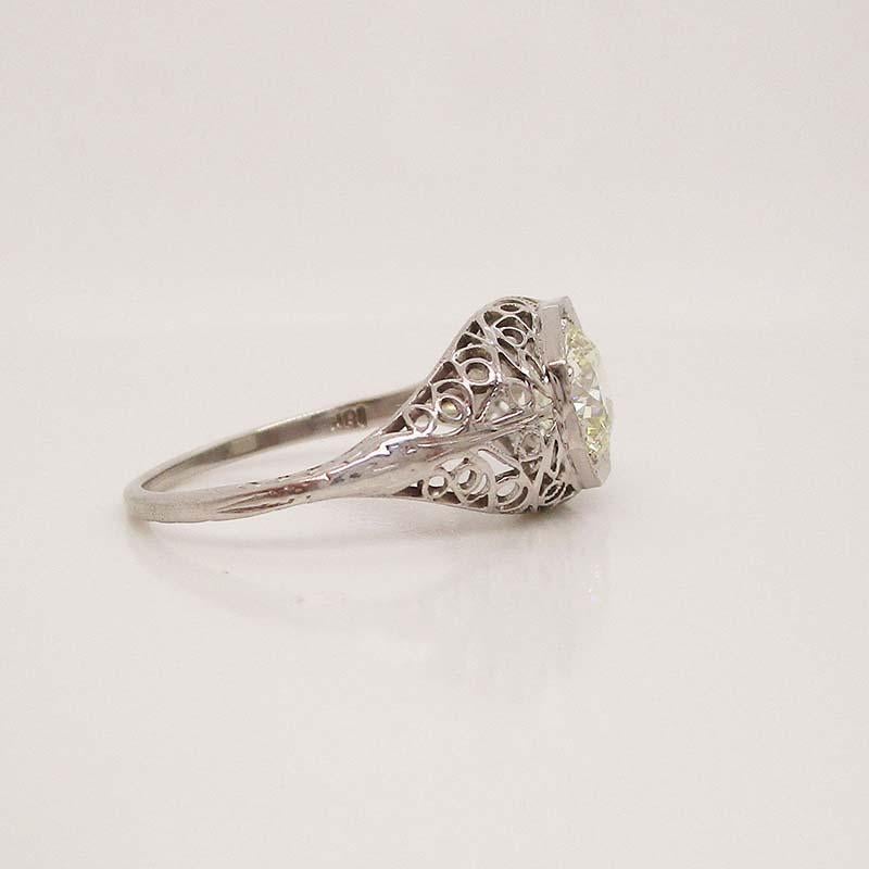 This is an absolutely stunning Art Deco ring from 1920 in 18k white gold with lovely filigree work and a breathtaking 1.00 carat diamond center stone. The delicate detail of the filigree carries down into the shoulders of the ring and continue in