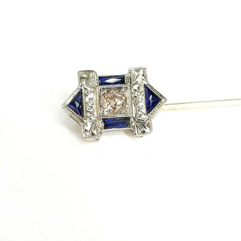  Classic art deco style pin with beautiful blue sapphire and round cut diamond crafted in 18K white gold.
Specifications:
    main stone: round diamond
    additional: blue sapphire tr/bg
    carat total weight: n/a
    color: I
    clarity: VS
   