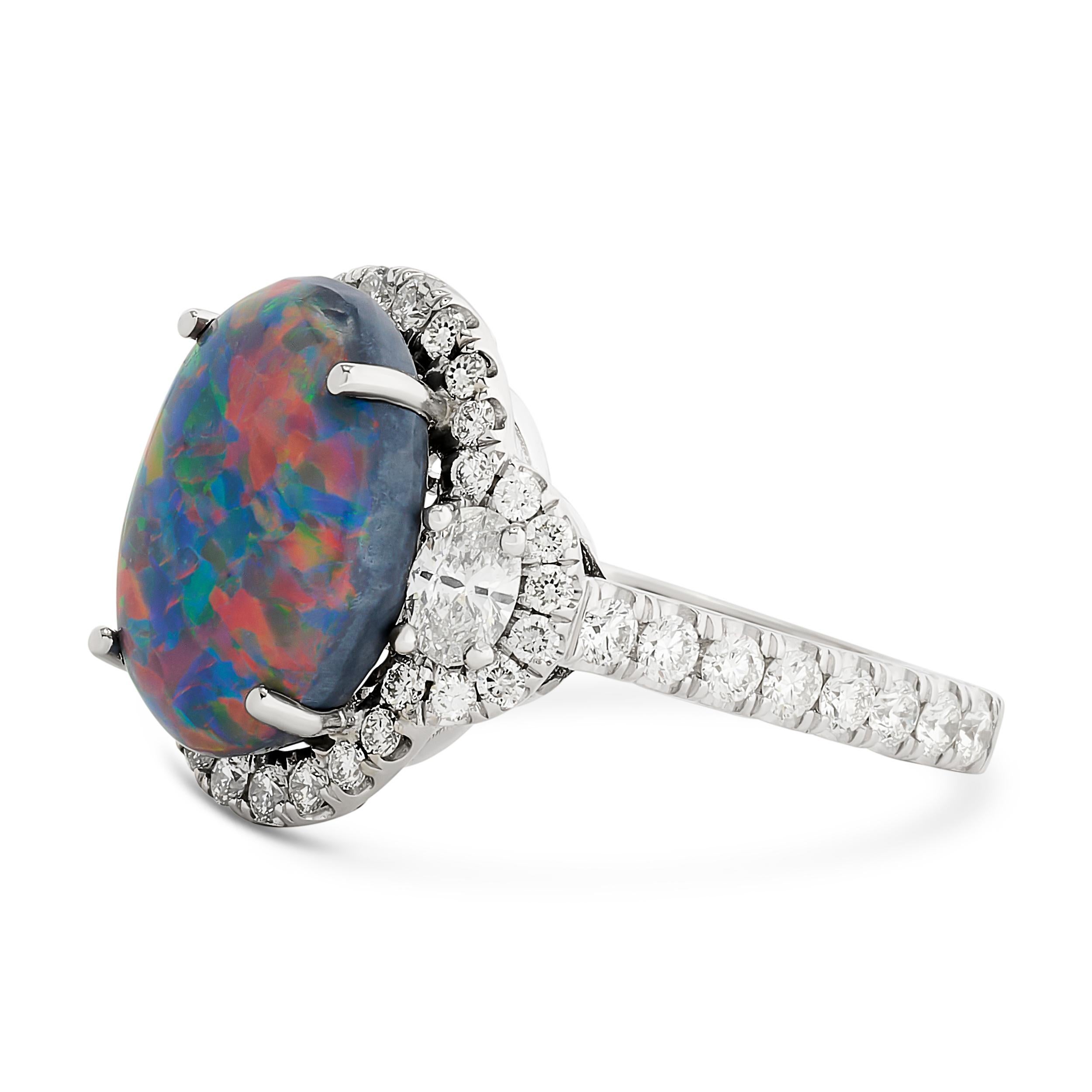 The exquisite black opal ring, adorned with shimmering diamonds, captivates with its mysterious beauty, casting a spell of elegance and intrigue. 
The center black opal weighs approximately 5.01 carats and is accompanied with a GIA Black, no