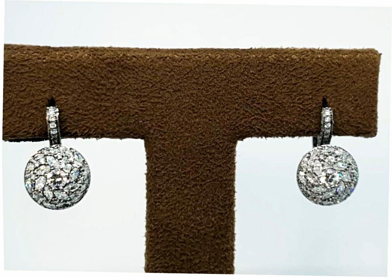 These earrings delicately crafted, are a modern interpretation of clusters. Manufactured in 18 karat white gold, brilliant cut round and fancy shape diamonds are set in serendipity complementing each other. A detailed back, mill grain on the borders