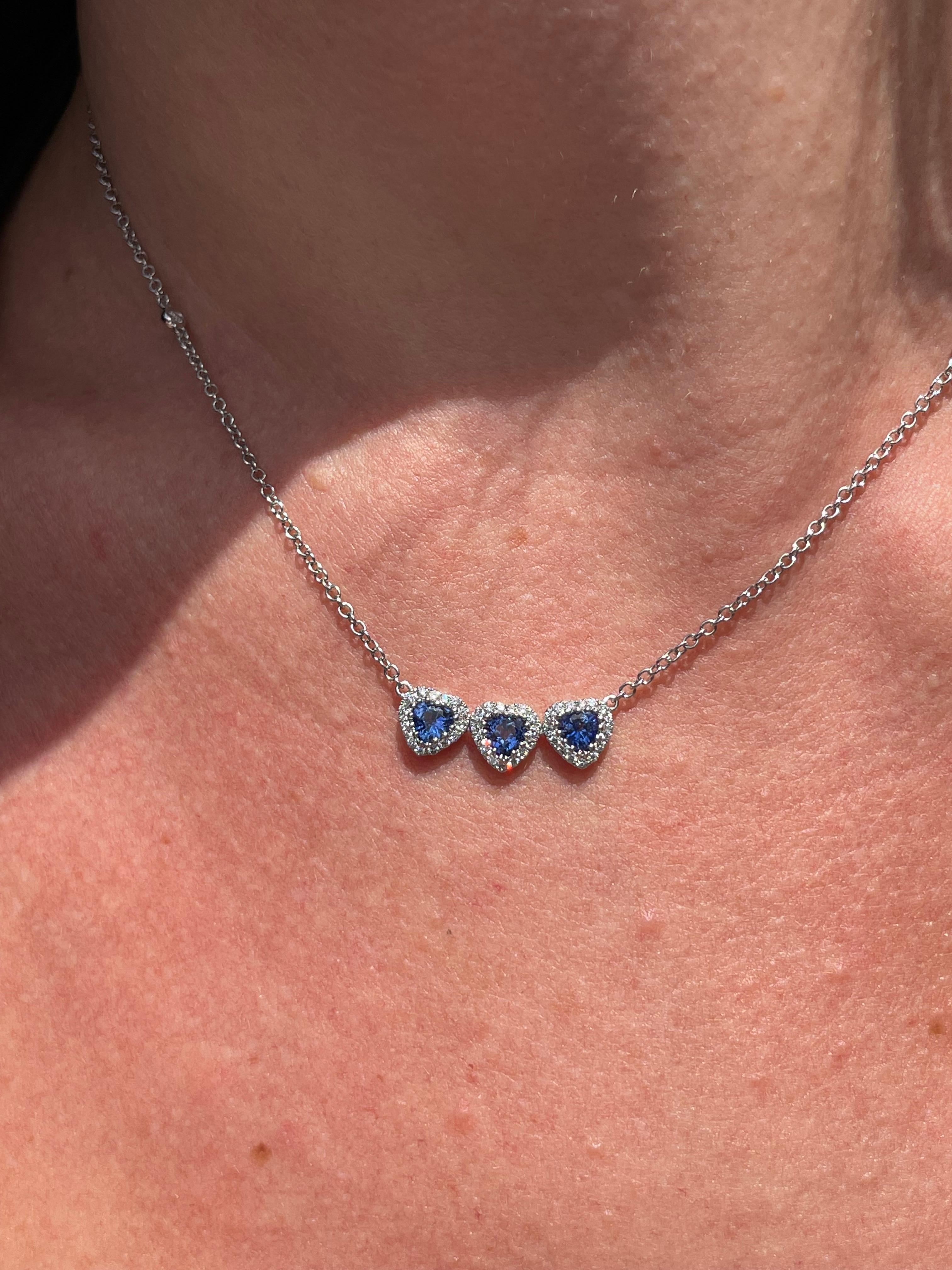 18 karat white gold necklace with a triple heart motif pendant. It showcases 3 heart shape blue sapphires weighing a total carat weight of 0.87 carats and 49 pave diamonds weighing a total carat weight of 0.41 carats.