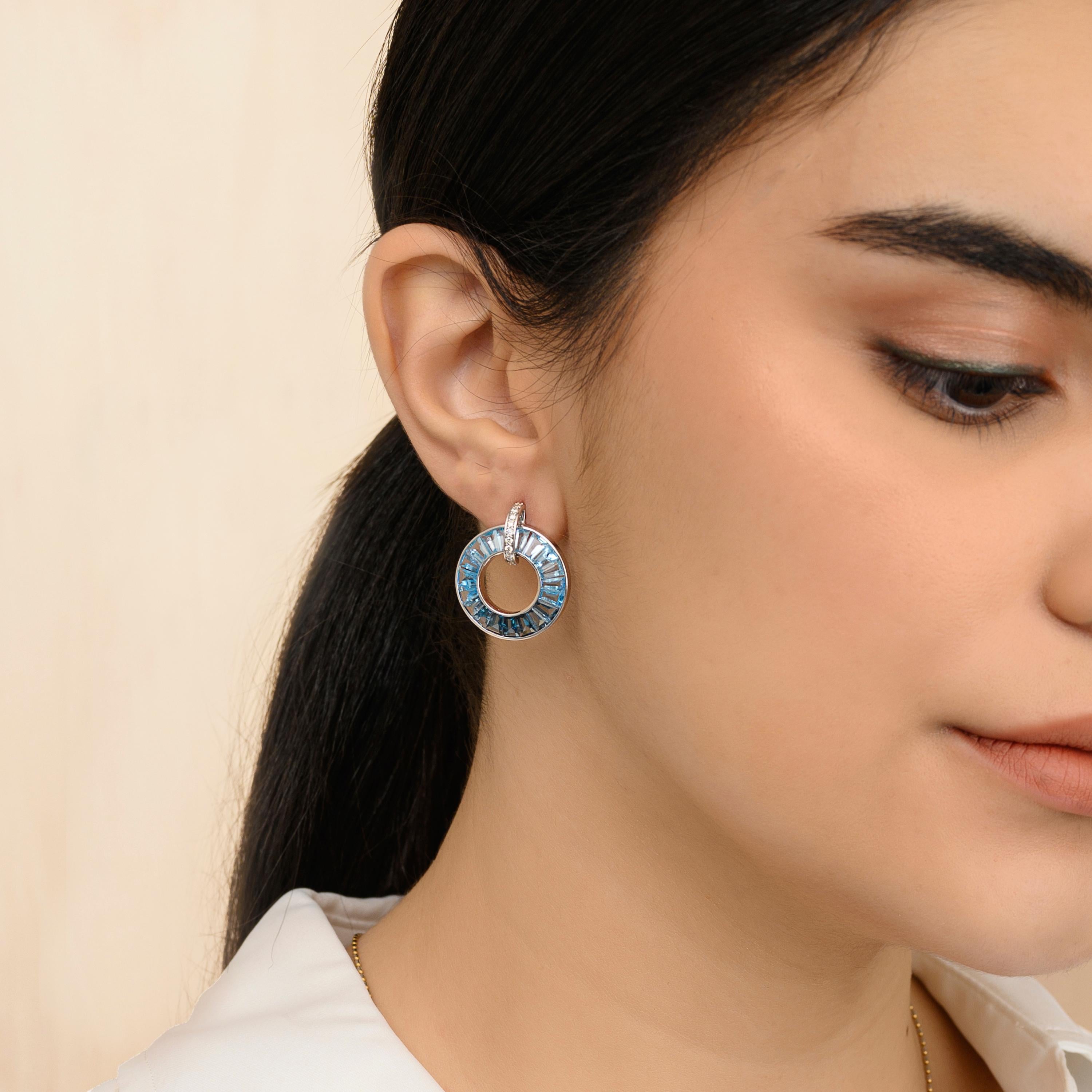 These absolutely stunning 18K White Gold Blue Topaz Diamond Circle Earrings is a symphony of elegance and sophistication. Crafted in radiant white gold, these earrings showcase the mesmerizing beauty of three types of blue topaz gemstones: Sky,