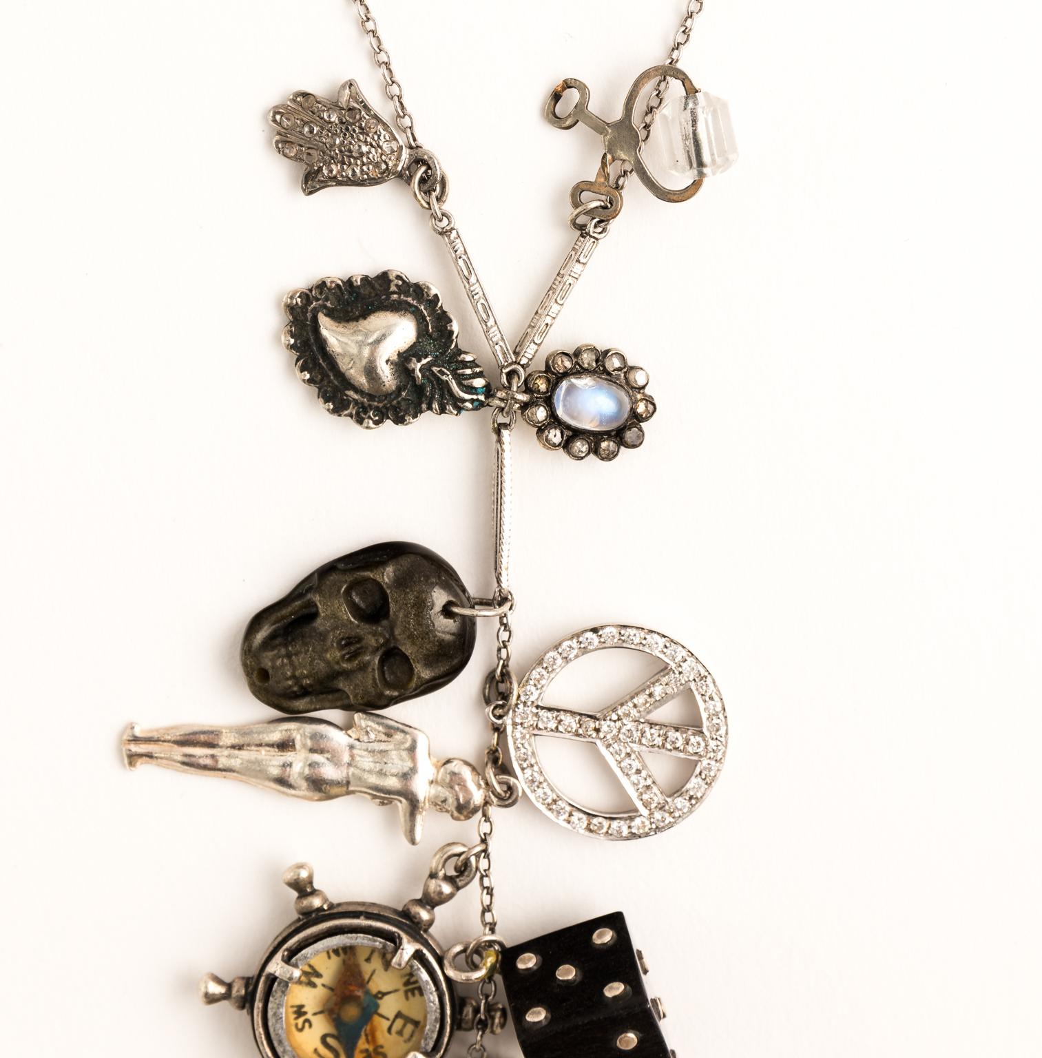 18 Karat white gold necklace with various charms featuring: a peace sign, Moonstone diamond florets with compass in Ebony, and black mother of pearl charms. The center black enamel and Marcasite clock is fully functional along with the compass and