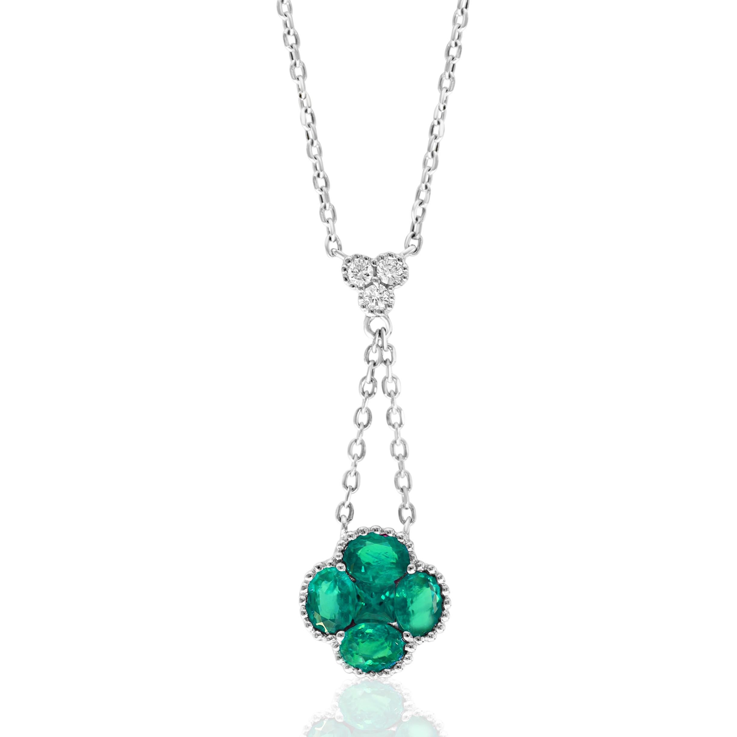 This beautiful necklace features 0.85 carat total weight in natural emeralds in a clover like shape that drops on a double chain from a trio of 0.07 carat total weight in three round diamonds. It is accented by milgrain detailing and set in 18 karat