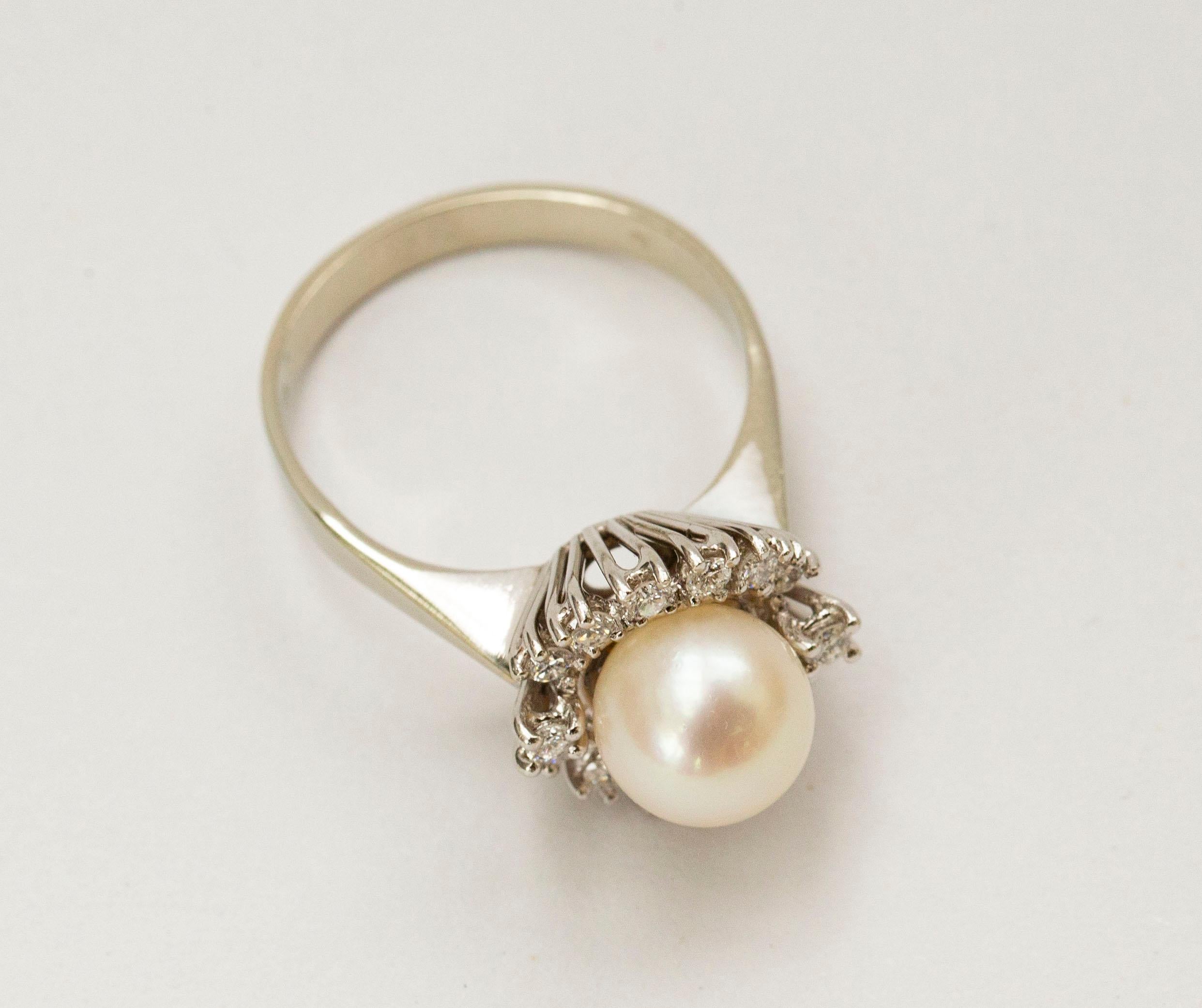 An 18 kt. white gold entrourage ring /cluster ring with a pearl and diamond cluster. The central freshwater pearl is surrounded by fourteen brilliant cut diamonds of the weight of approx. 0.28 ct. The ring is stamped with 750 that stands for the 18