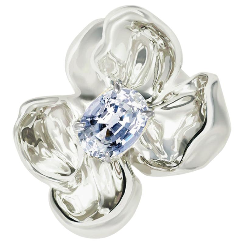 This Magnolia Flower contemporary sculptural brooch is crafted in 18 karat white gold and adorned with a clear and shiny light blue sapphire, weighing 0.65 carats. The water-like surface of the gemstone reflects and multiplies the light, mirroring