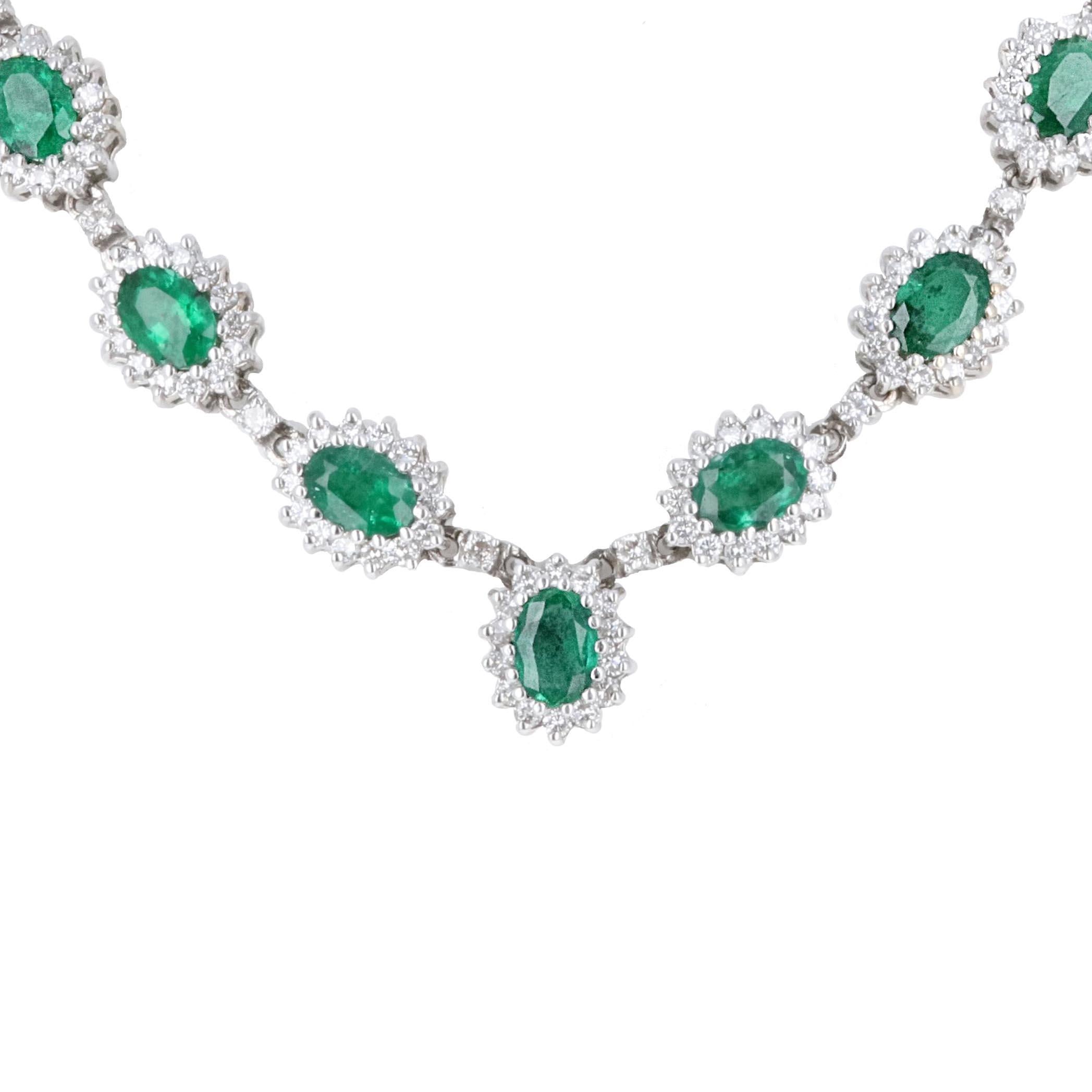 18 karat white gold diamond and emerald drop necklace. There are 11 emeralds with an estimated total weight of 11 carats, making each emerald around 1 carat.  Diamonds surround and adorn the oval cut emeralds. The diamond halo around each emerald