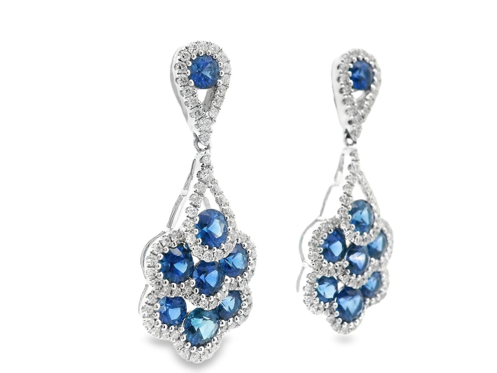 This is an absolutely breathtaking pair of earrings in 18k white gold with a stunning selection of bright white diamonds and rich royal blue sapphires. The earrings have a classic dangle layout that is fully articulated for an excellent range of