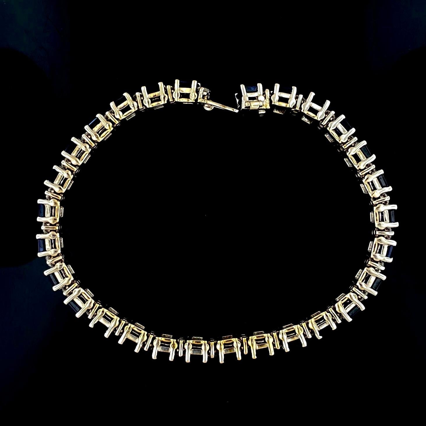 Tennisarmband mit Saphiren und Diamanten aus 18 Karat Weißgold.

Das Armband wiegt ungefähr 30 Gramm, ist 7 Zoll lang und 0,25 Zoll breit. Es gibt 28 Saphire im Smaragdschliff mit einem Gewicht von ca. 21 Karat, 56 natürliche runde Diamanten im