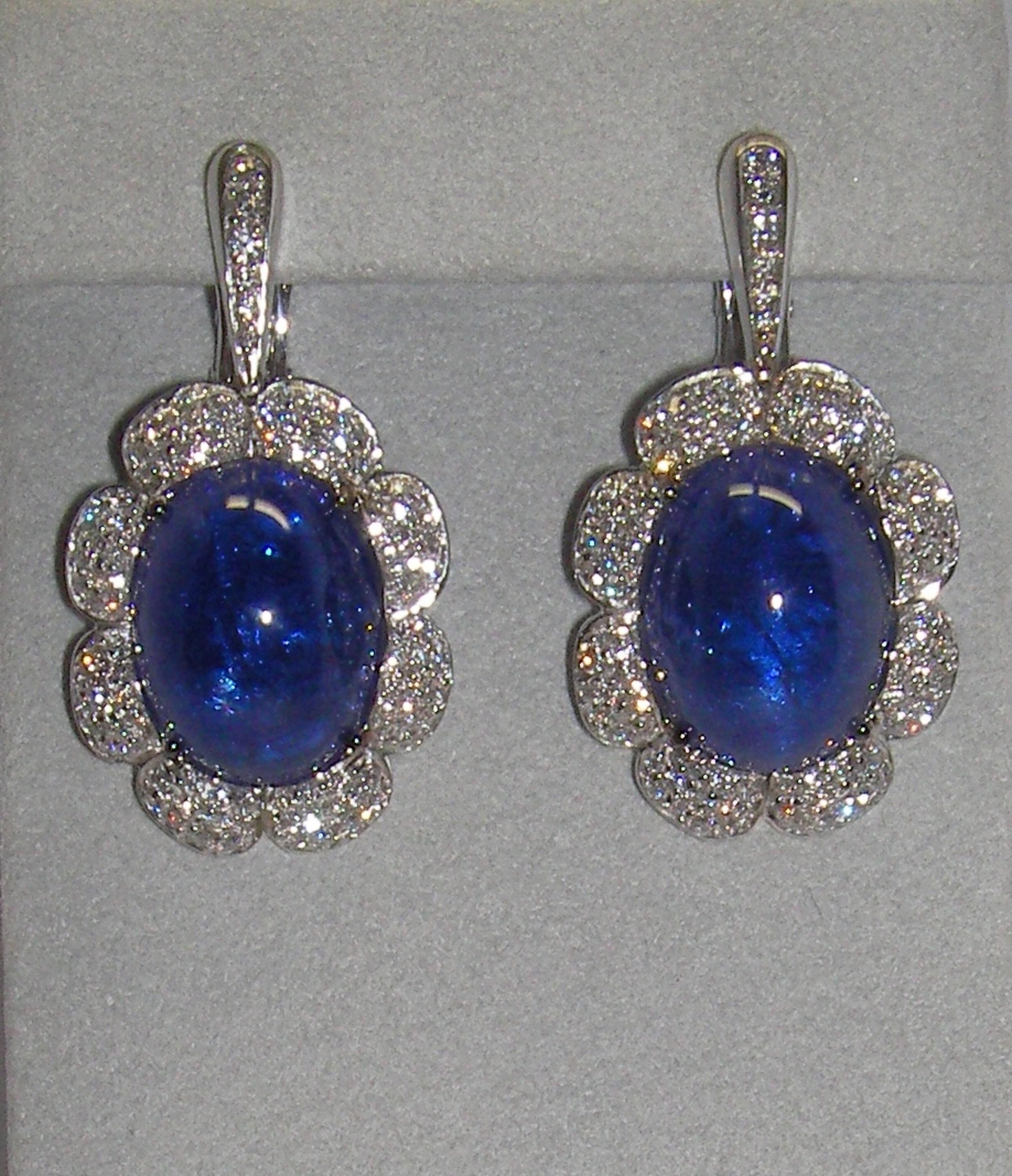 These stunning 18 Karat White Gold Drop Earrings full of Diamonds highlighting a Tanzanite oval shaped center stone on each earring. These earrings are a perfect compliment to our 18 Karat White Gold Diamond and Tanzanite Cocktail Ring and 18 Karat