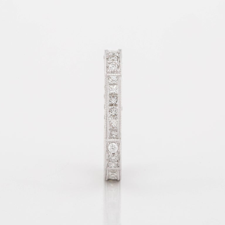 Eternity band composed of 18K white gold with 18 princess-cut diamonds and 42 round brilliant-cut diamonds; G-H color and VS1-2 clarity, with a total carat weight of 2.60.  The band features millegrain work as well as a more squared shape.  It is