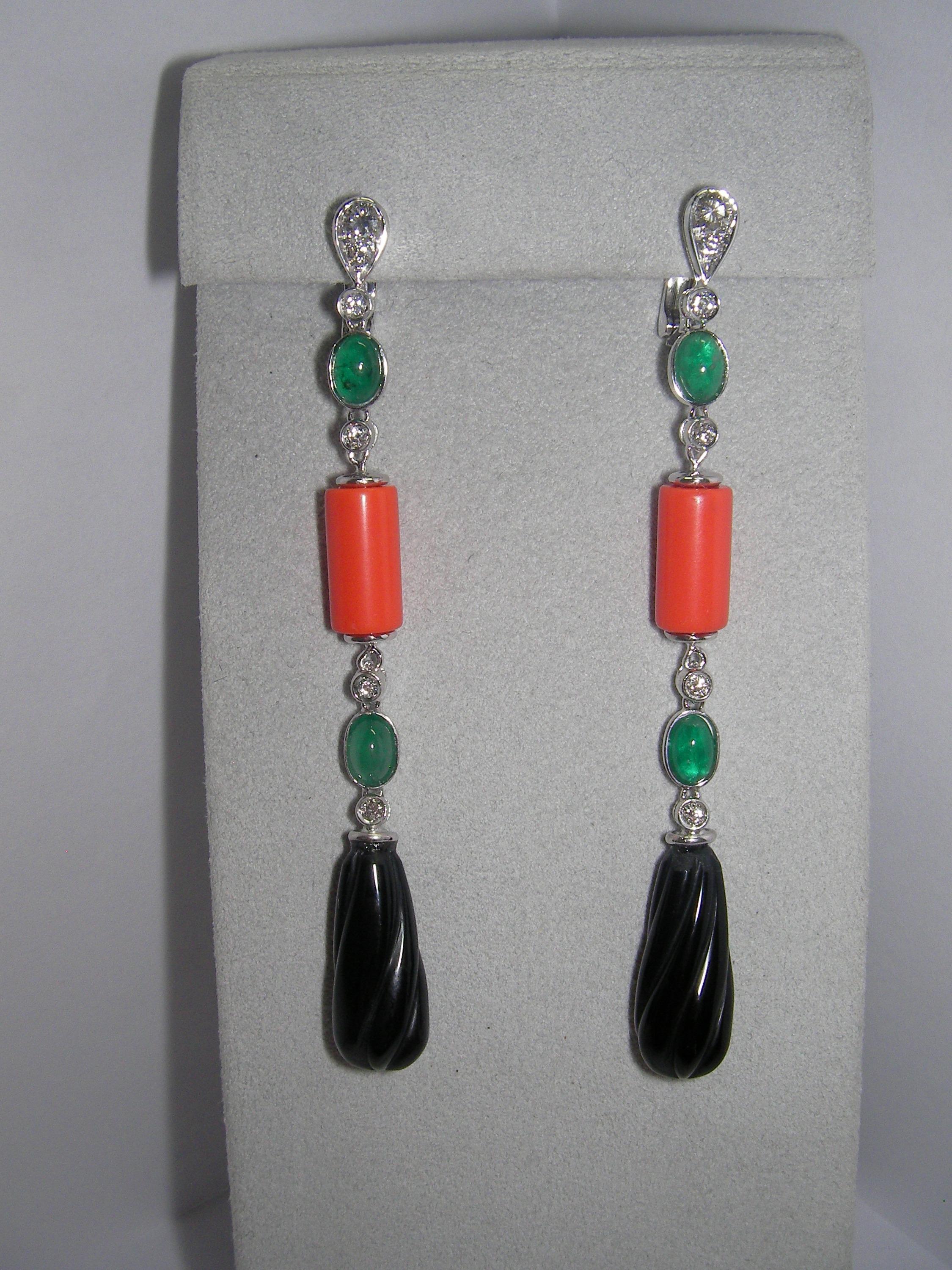 These 18 Karat White Gold Dangle Earrings will steal the show! 
Each earring features a diamond based, followed by a strand of two cabochon oval cut Emeralds, a cylindric recon Coral and pear-shaped carved Onyx. 
This is the perfect gift for your
