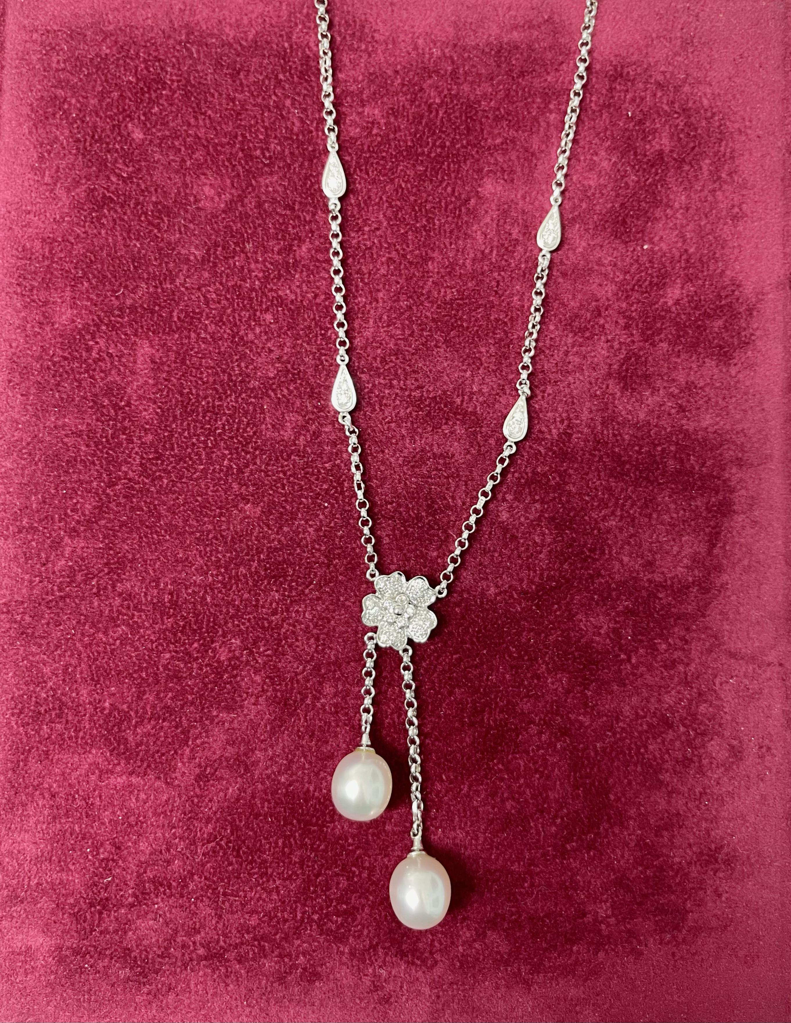 Beautiful and shining necklace made in 18 karat white gold embellished in the center by a flower covered by diamonds where two white pearl pendant from there.
The necklace is it also embellished by four drops, two on the left side and two on the