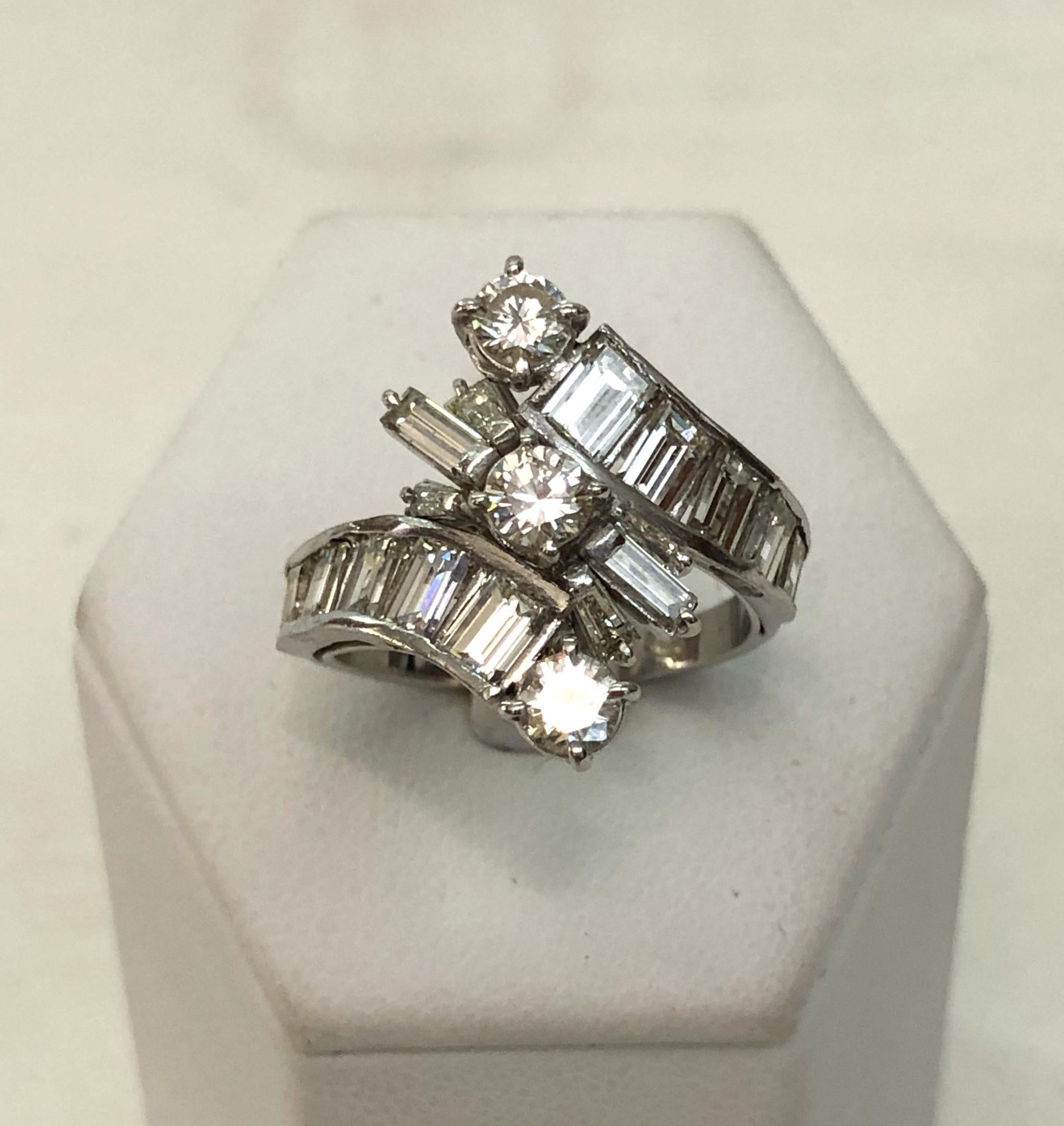 Anello in oro bianco 18 carati disposto in direzioni opposte, con tre diamanti brillanti allineati al centro e i restanti diamanti con taglio baguette e affusolato, per un totale di 3 carati / Made in Italy 1970s
Anello misura US 6.75